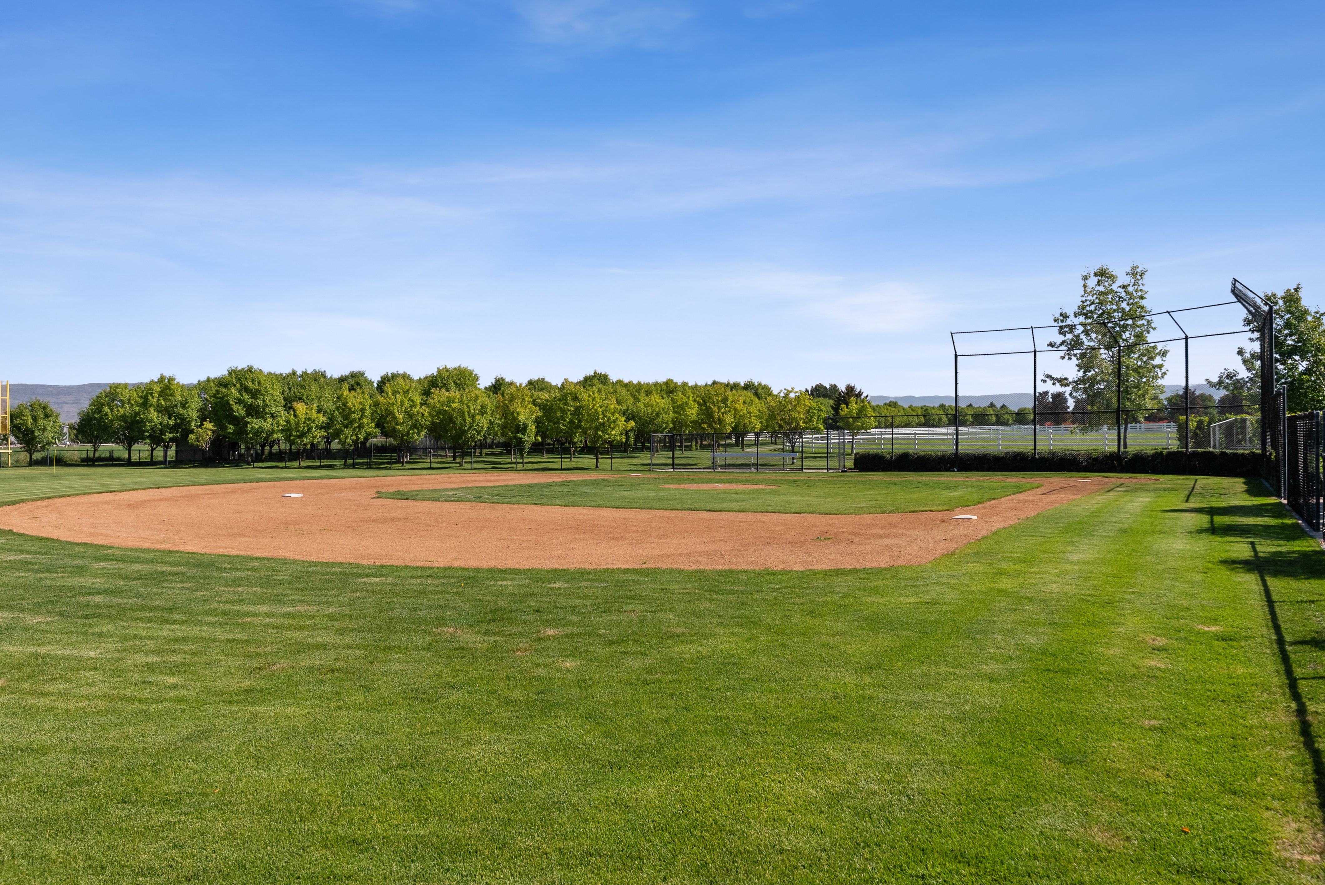 Baseball field featuring a manicured outfield, dirt infield, and surrounding chain-link fencing