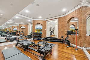 Gym featuring brick wall, crown molding, recessed lighting, and wood finished floors