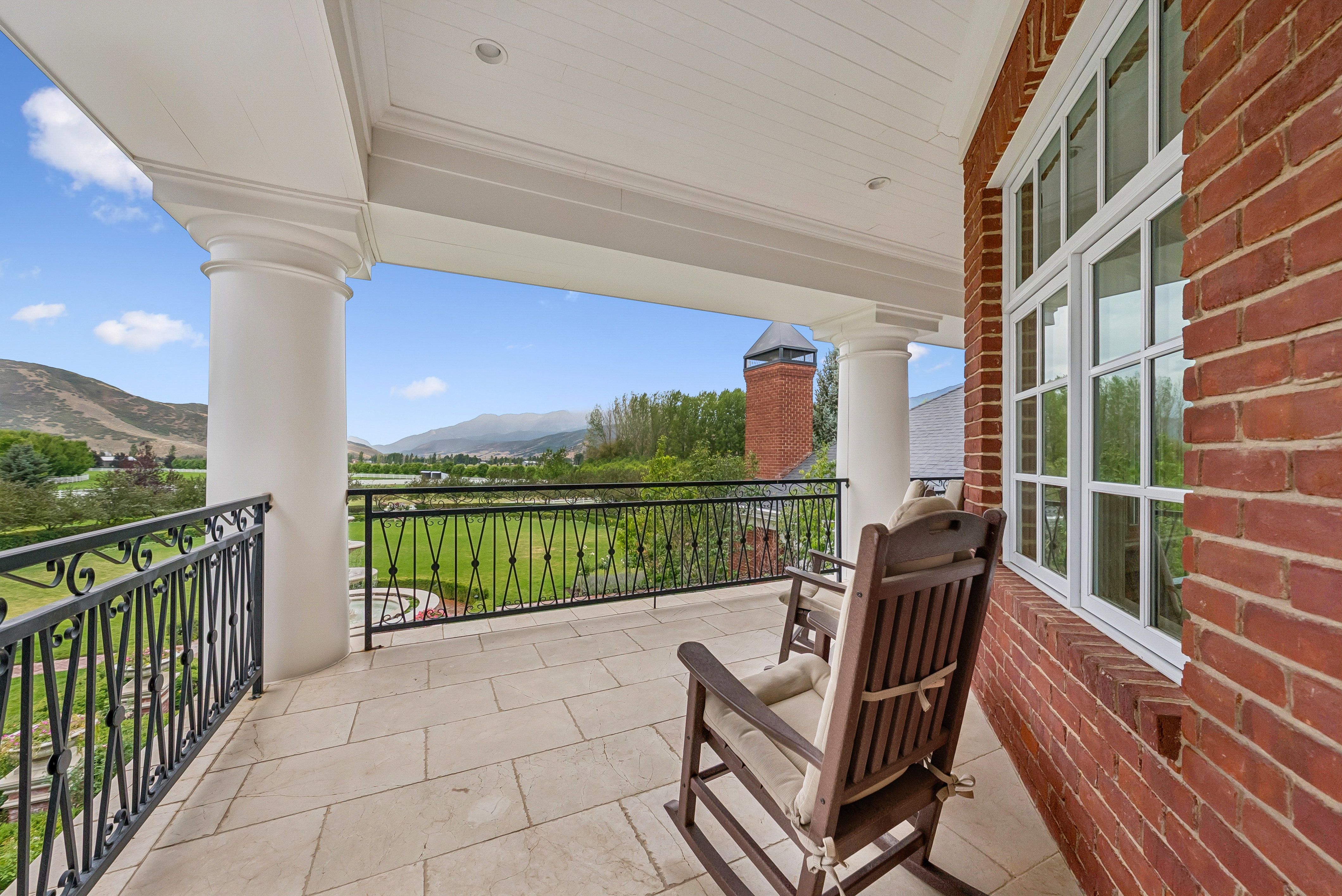 Covered balcony featuring substantial columns and a full brick exterior