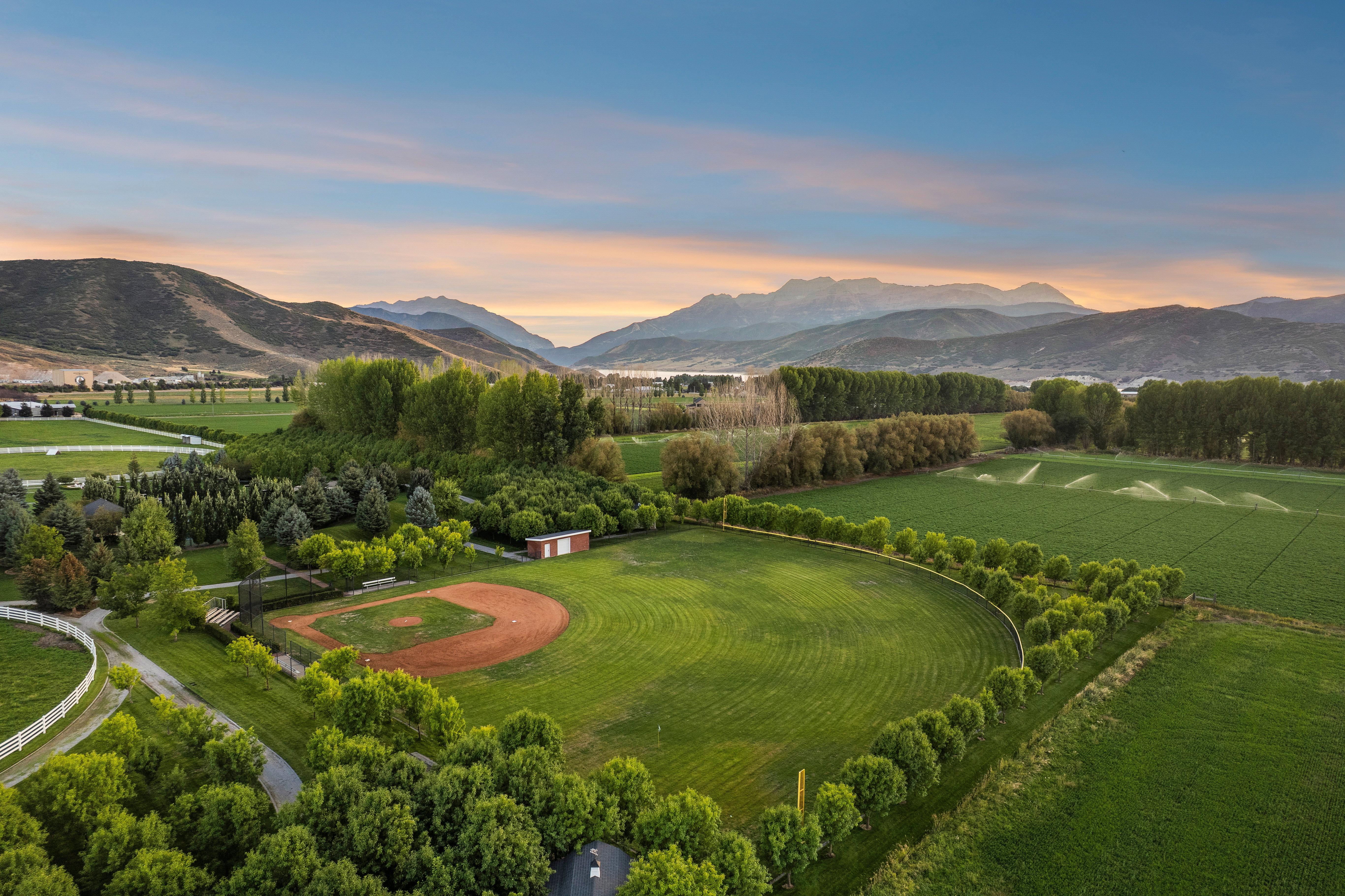 Expansive green acreage featuring a baseball diamond, mature trees, and a distant mountain range