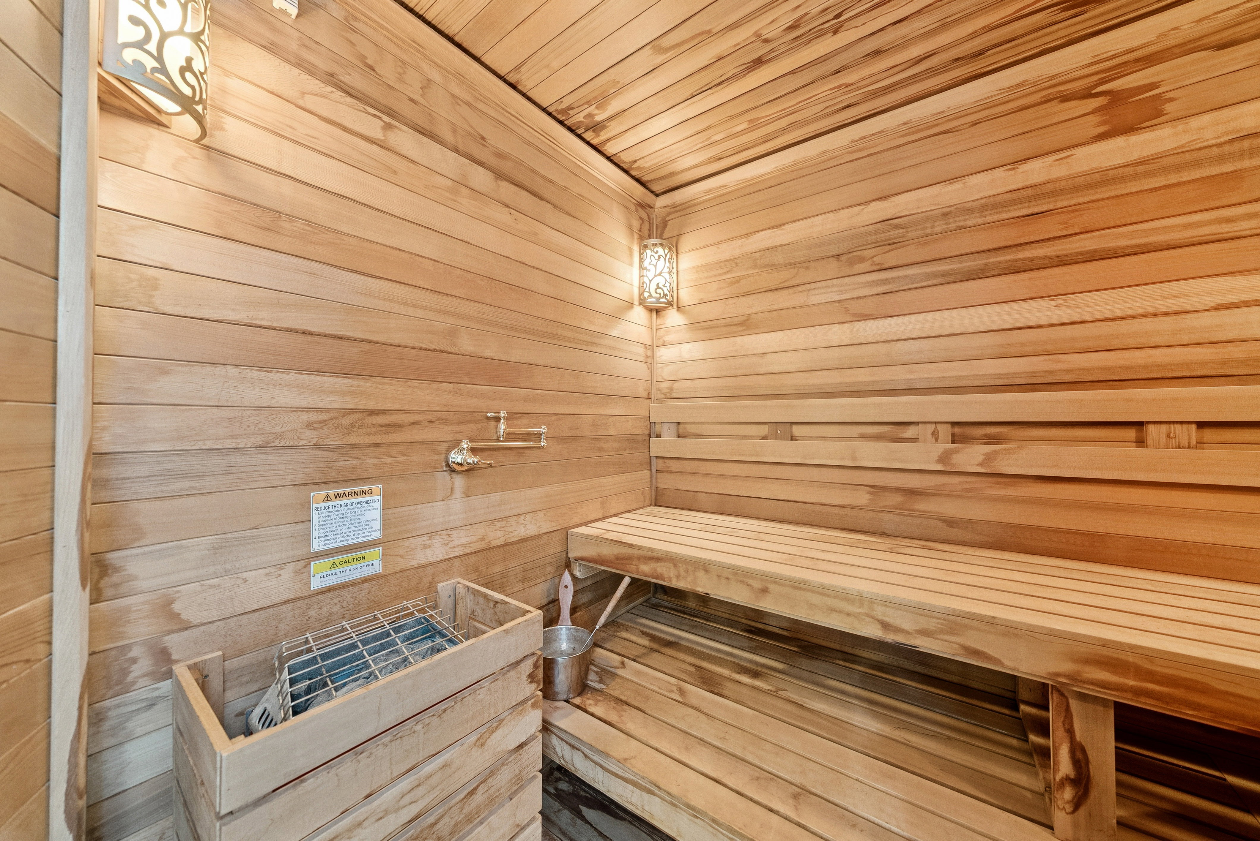 Dedicated sauna room featuring extensive wood paneling, built-in benches, and an integrated sauna heater