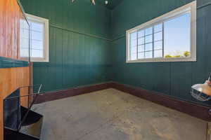Empty room with healthy amount of natural light, wooden walls, and unfinished concrete flooring