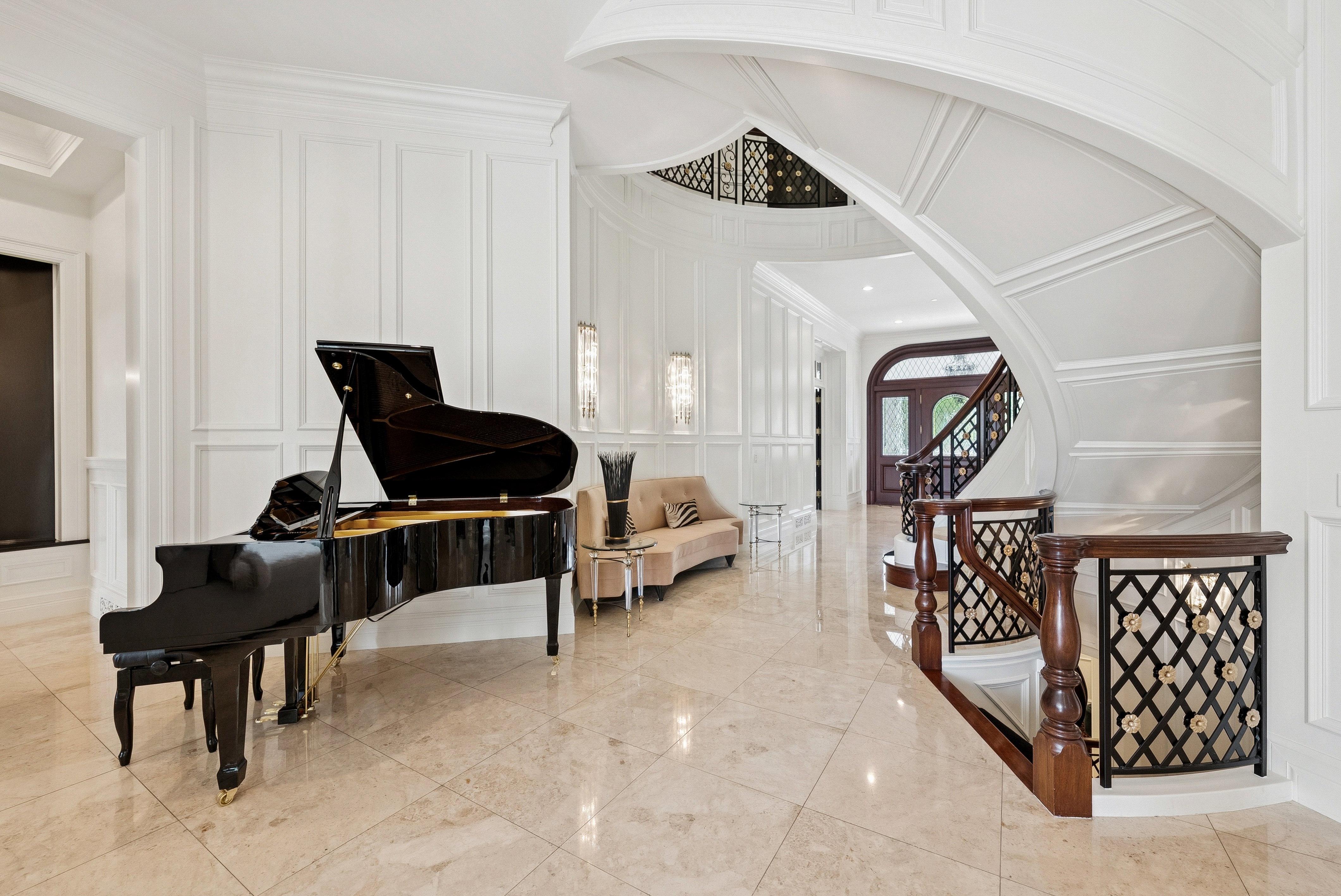 Grand foyer featuring polished tile flooring and an elegant curved staircase with decorative wrought iron balusters