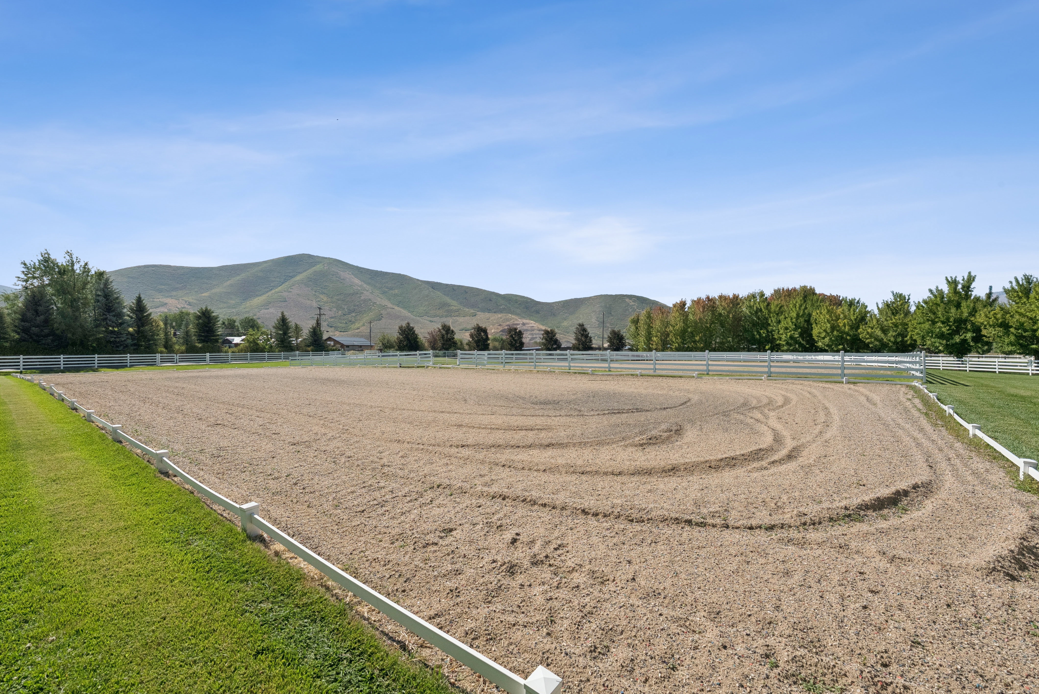 Expansive outdoor arena featuring sand footing and white perimeter fencing
