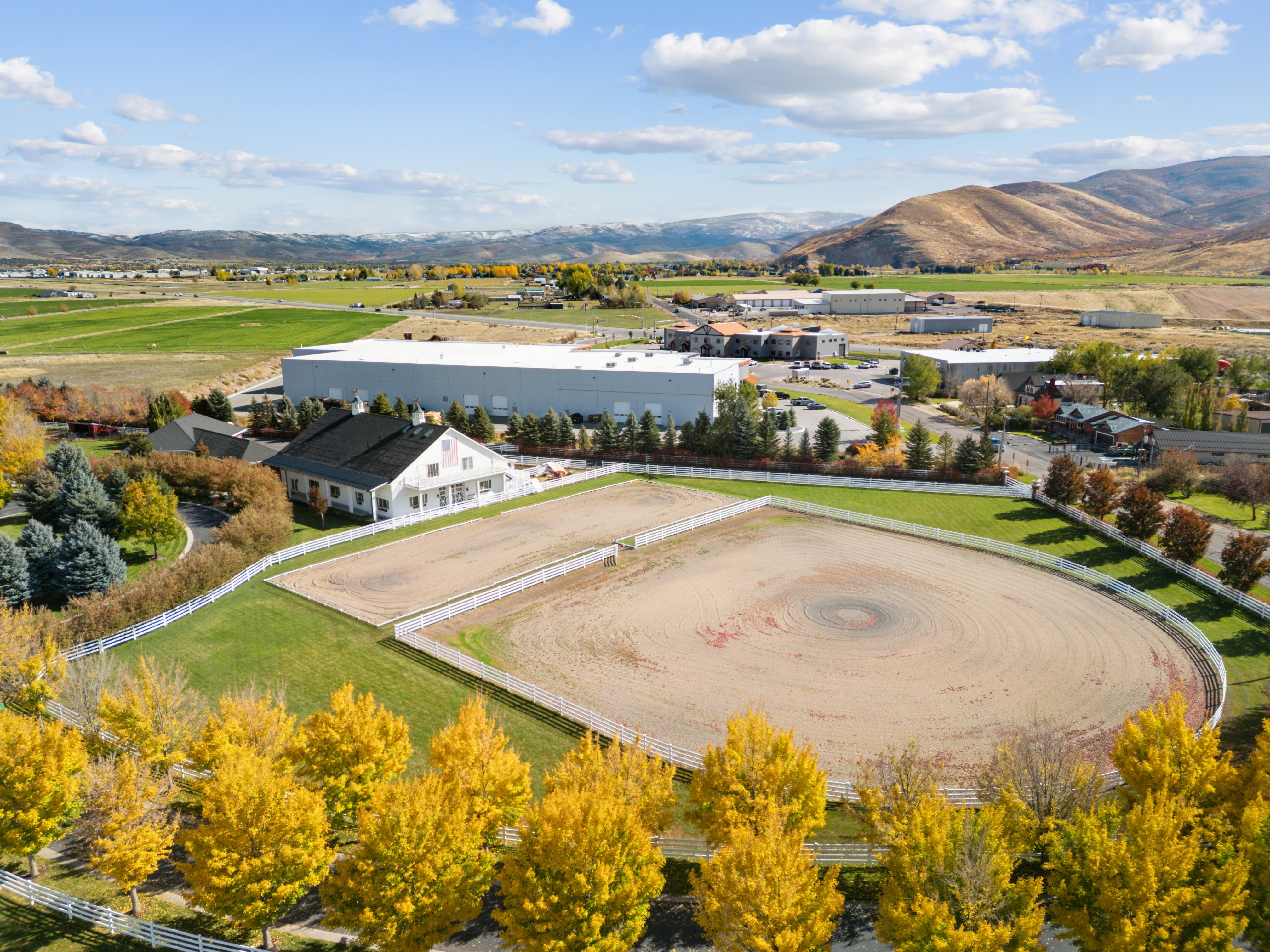 Expansive property featuring two large riding arenas and a white perimeter fence