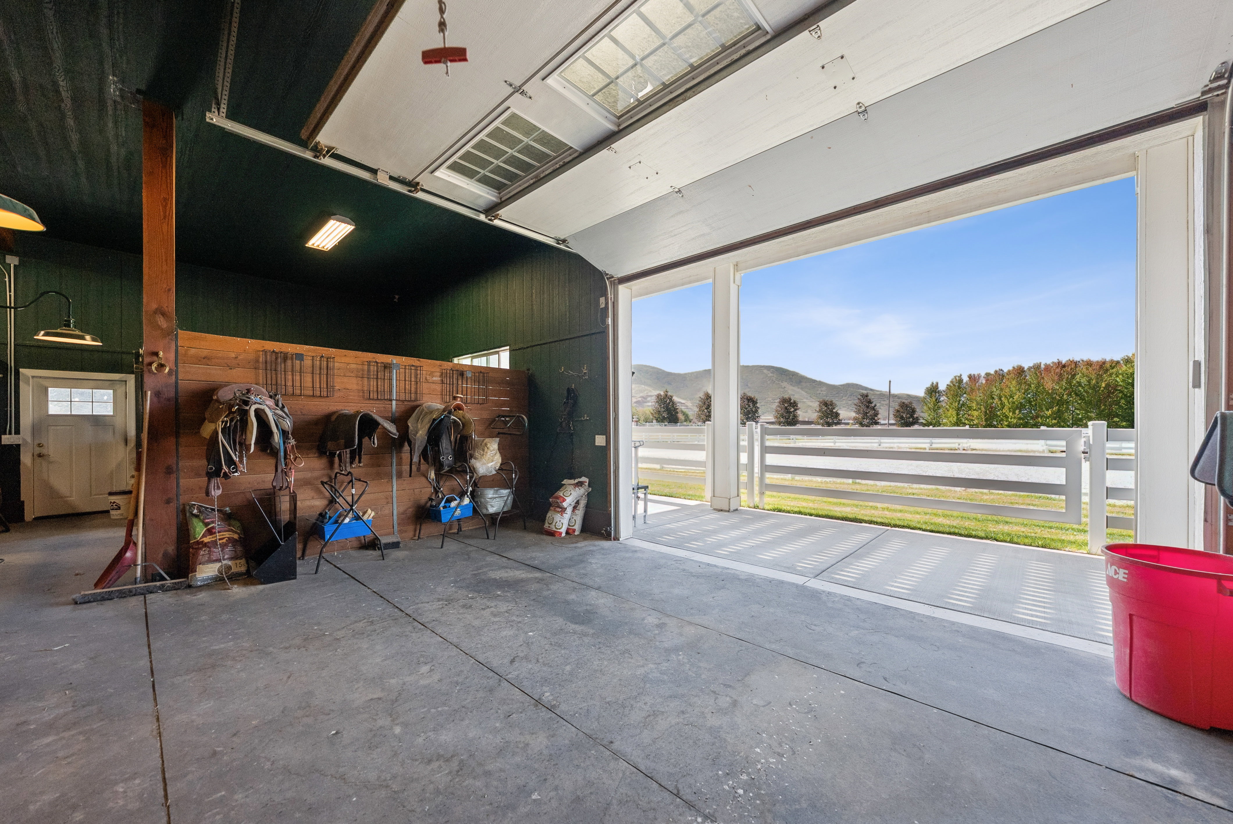 Spacious outbuilding with concrete flooring, dark green paneled walls, and exposed wood beam accents