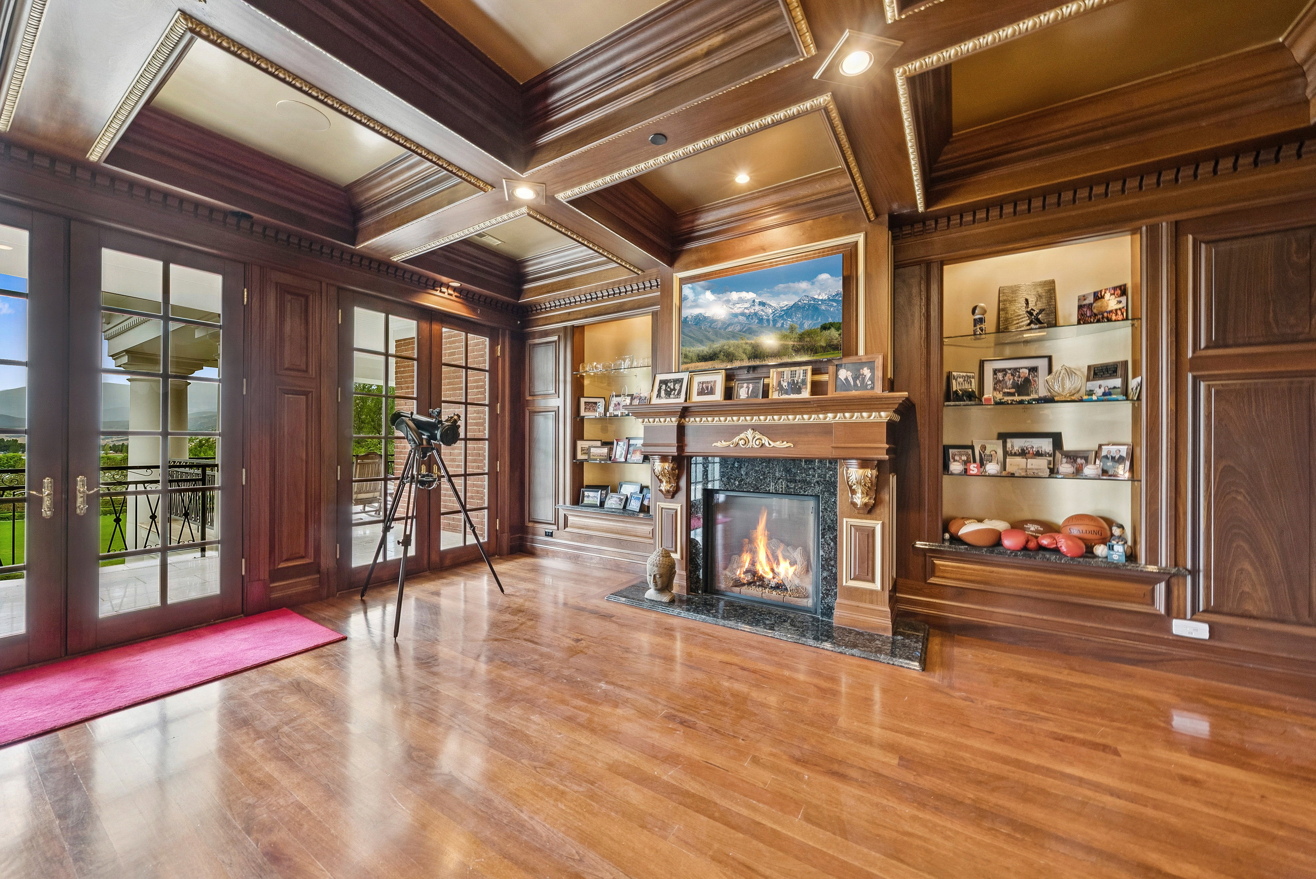 Hardwood flooring complements a detailed coffered ceiling and extensive wood paneling