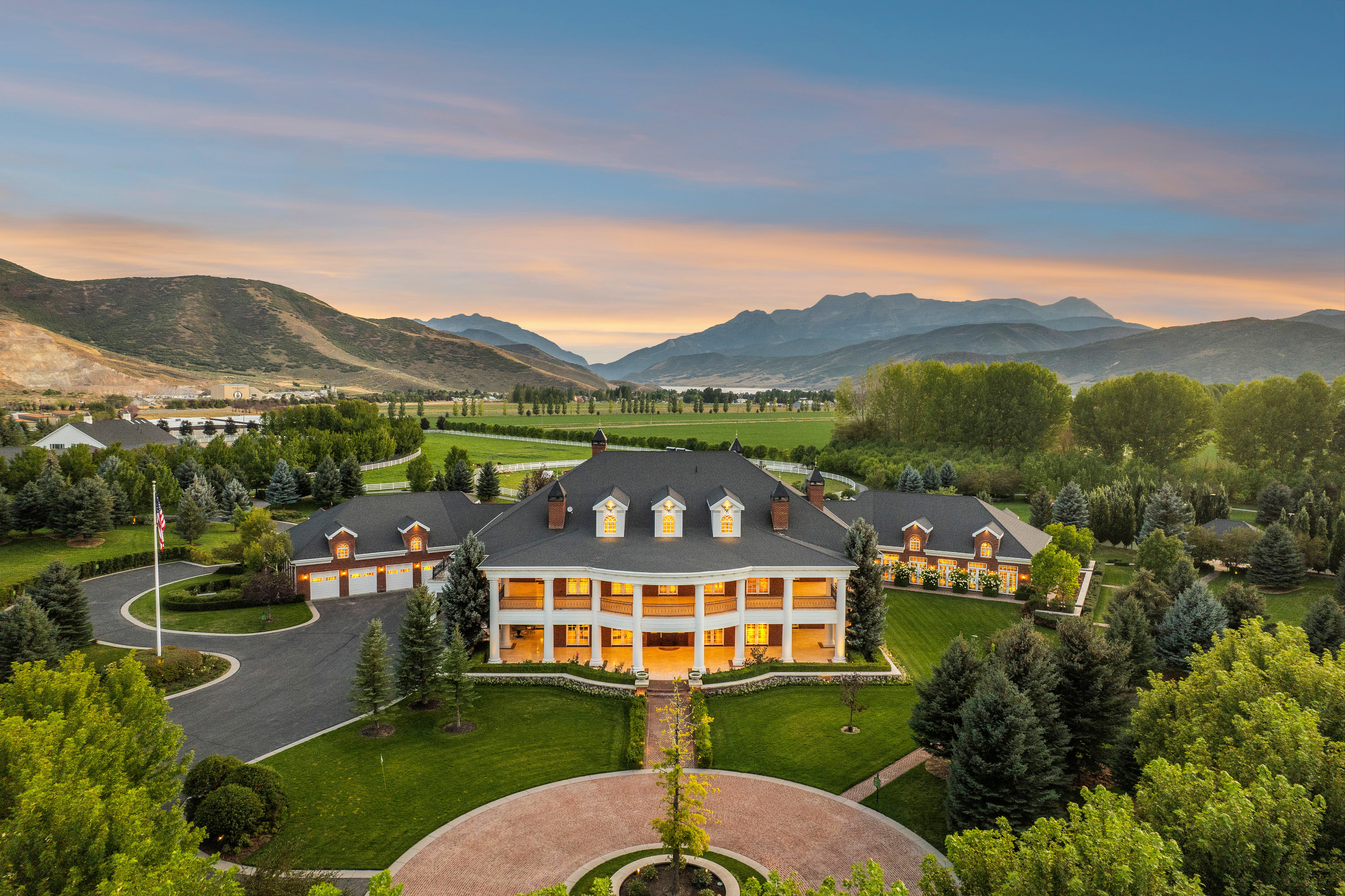 Expansive estate featuring a grand two-story colonial-style residence with a wide front porch and dormer windows