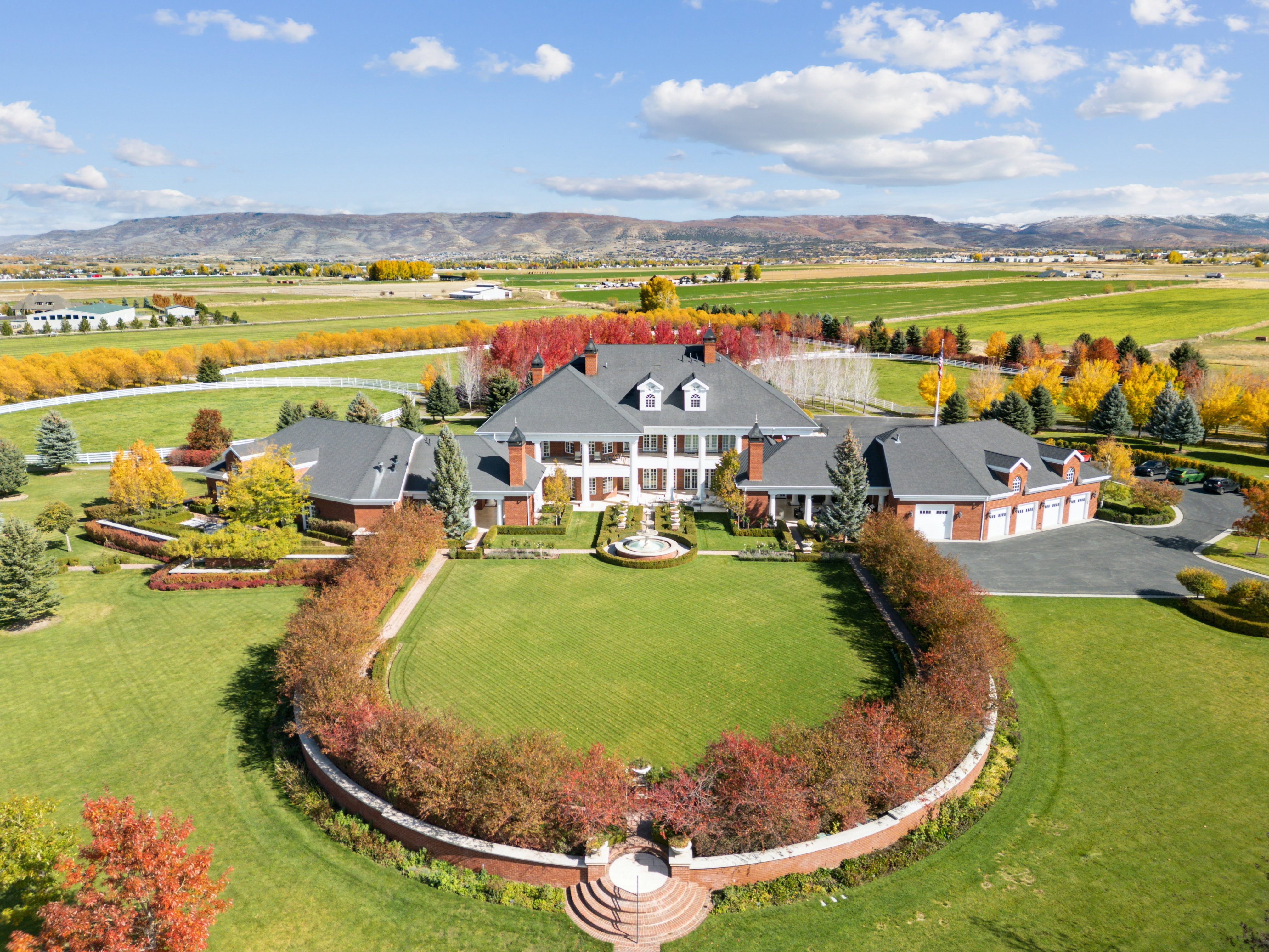 Expansive estate featuring a brick exterior, multiple dormer windows, and a circular driveway