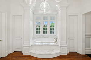 Bathroom with a bath and dark wood-style flooring