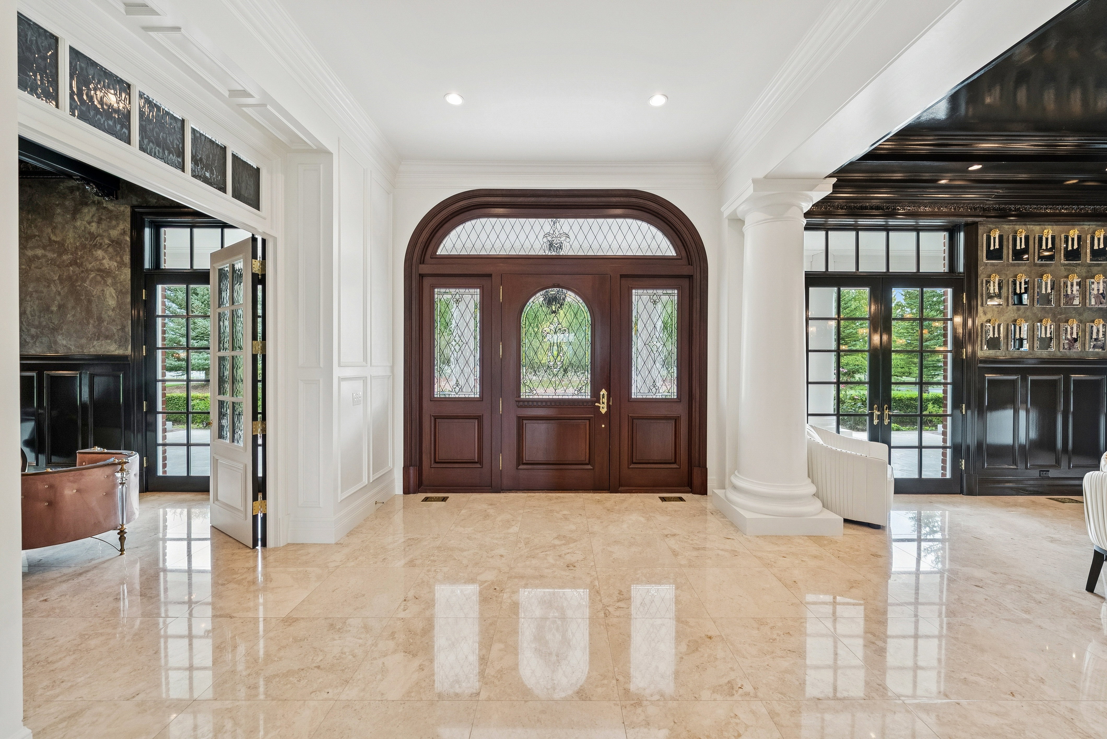 Grand foyer featuring a rich wood-finish arched entry door with leaded glass sidelights and transom
