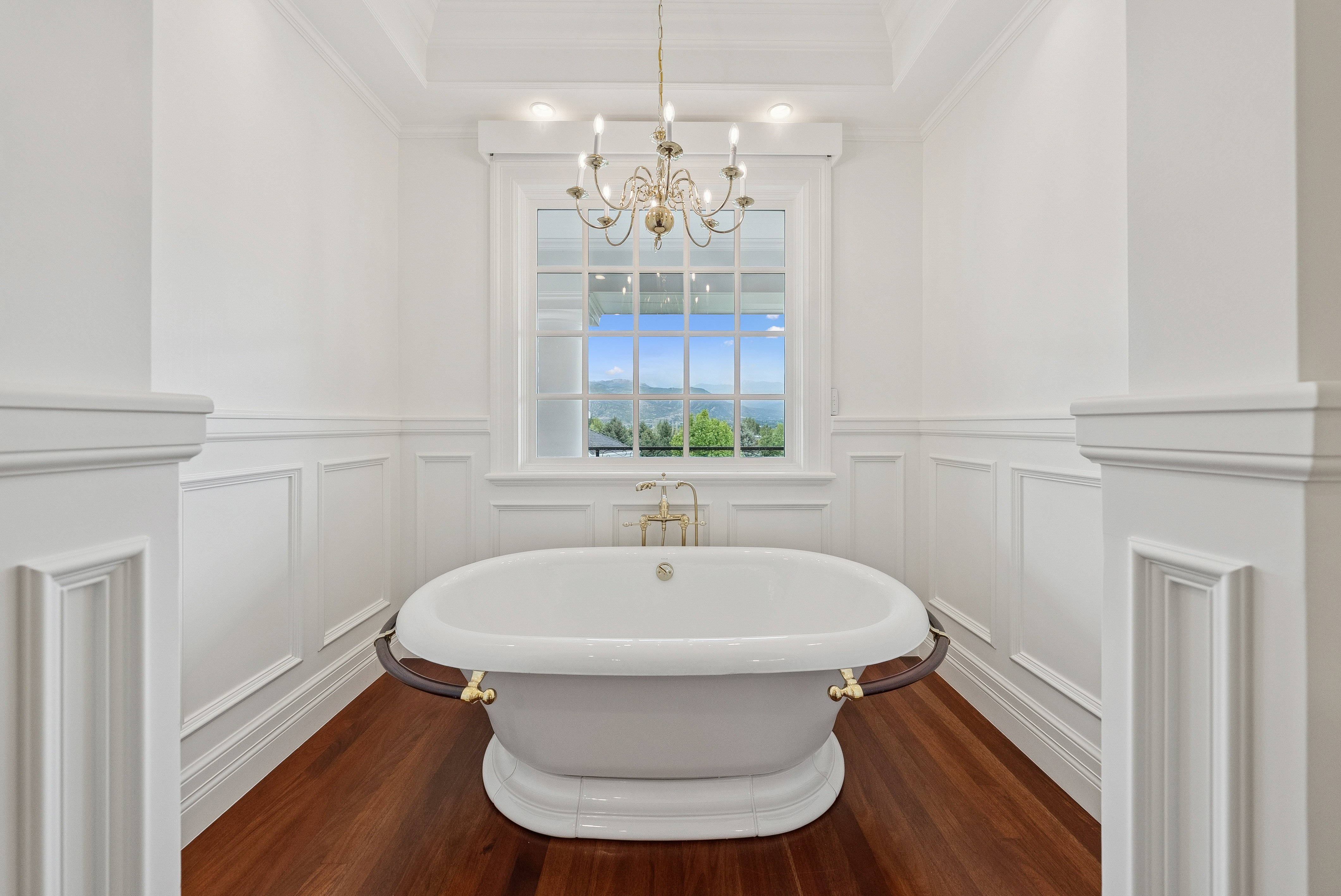 Freestanding soaking tub centered under a large window with mountain scenery