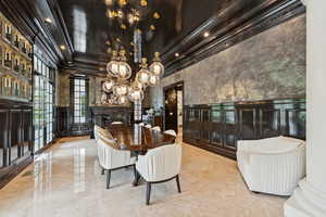 Dining space featuring a decorative wall, wainscoting, ornamental molding, a chandelier, and marble tiled floors