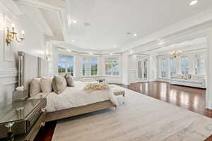 Bedroom with a chandelier, a decorative wall, dark wood-style flooring, recessed lighting, and crown molding