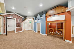 Additional living space with carpet flooring, lofted ceiling, and brick wall