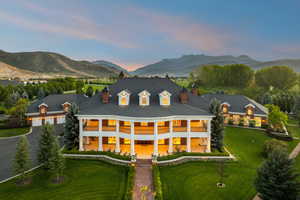 Rear view of house featuring a large porch, a mountain view, a chimney, and a lawn