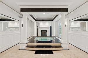 Living area with inlaid floor details, decorative columns, a fireplace, ornamental molding, and a decorative wall