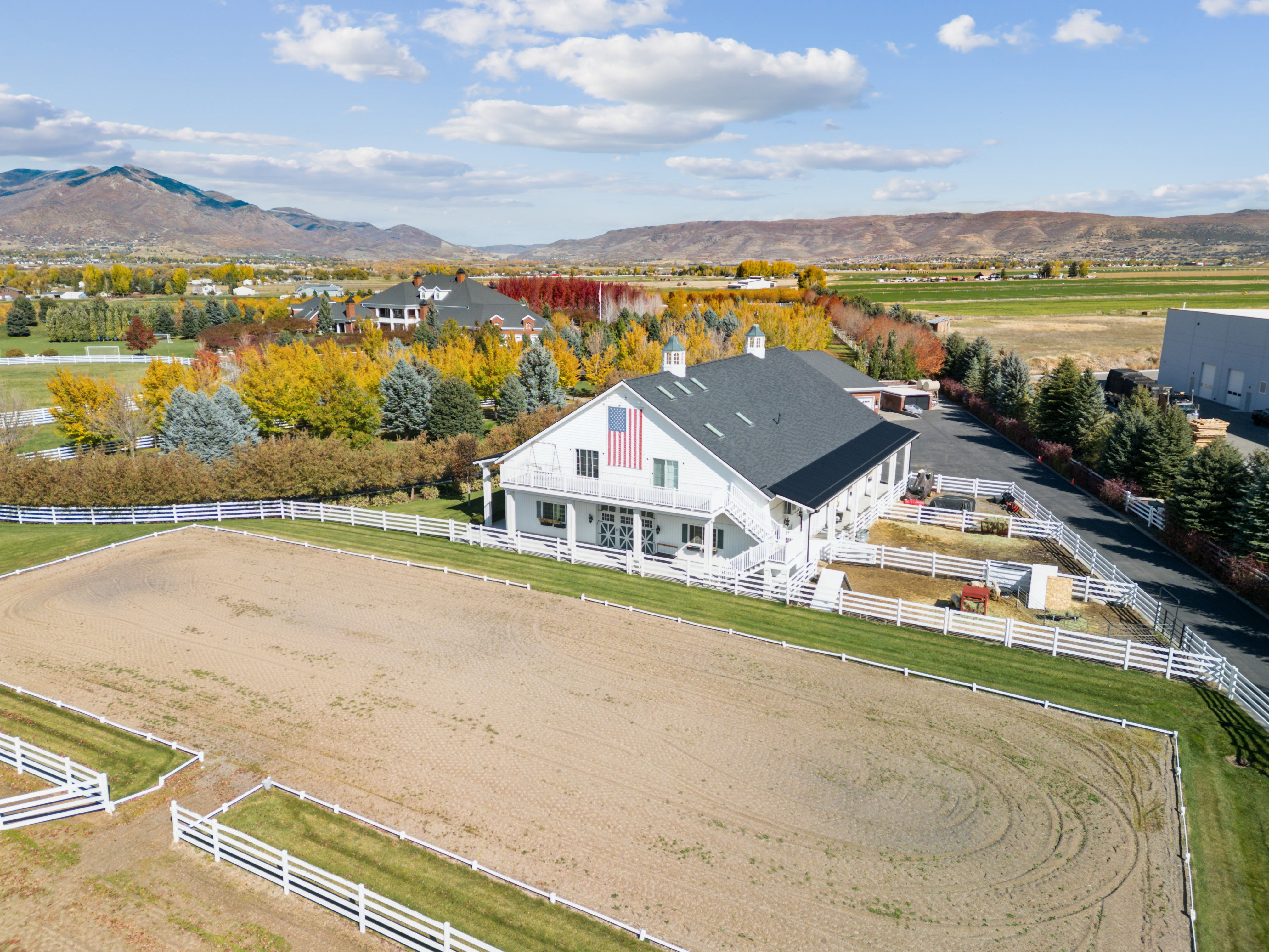 Large equestrian arena featuring sand footing and white fencing