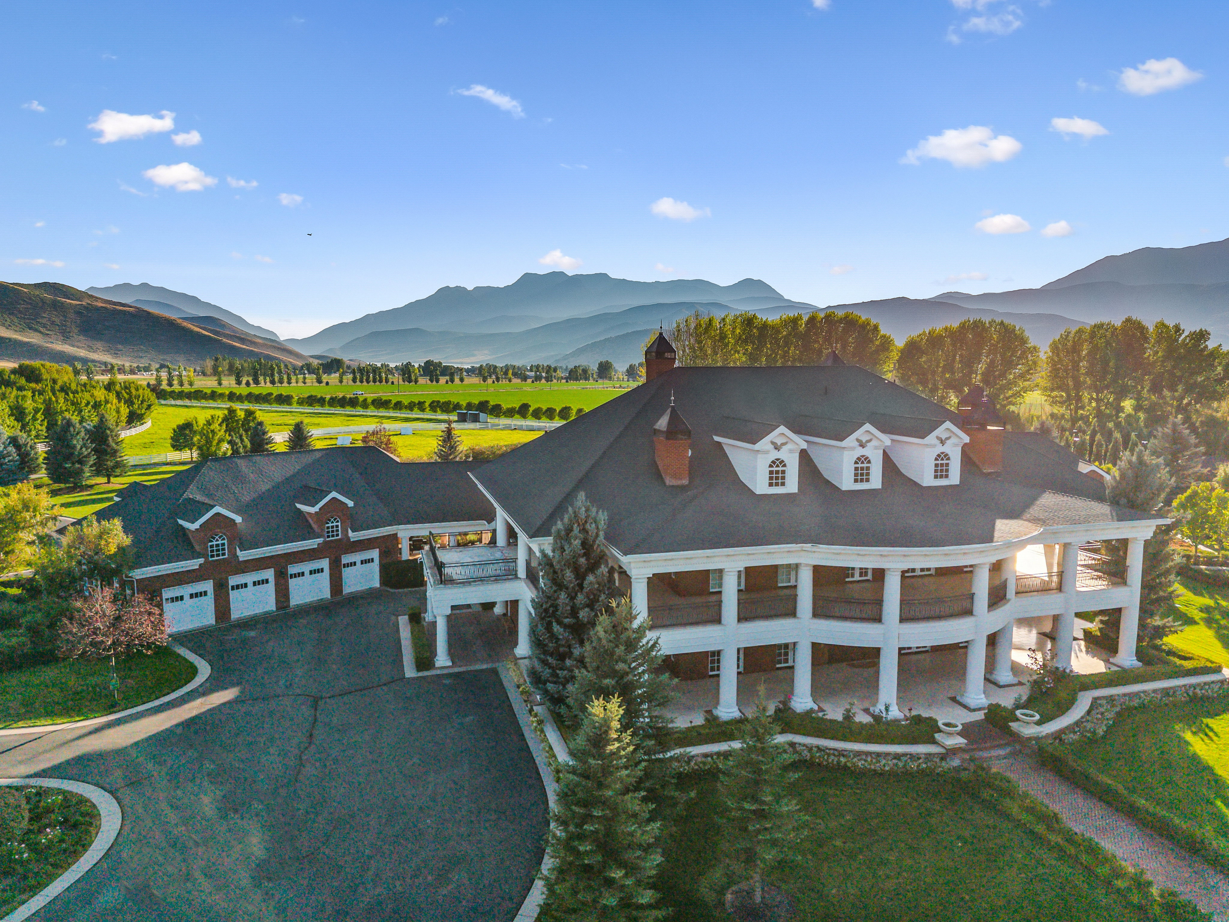 Grand estate featuring a columned wrap-around porch, multi-car garage, and a expansive driveway