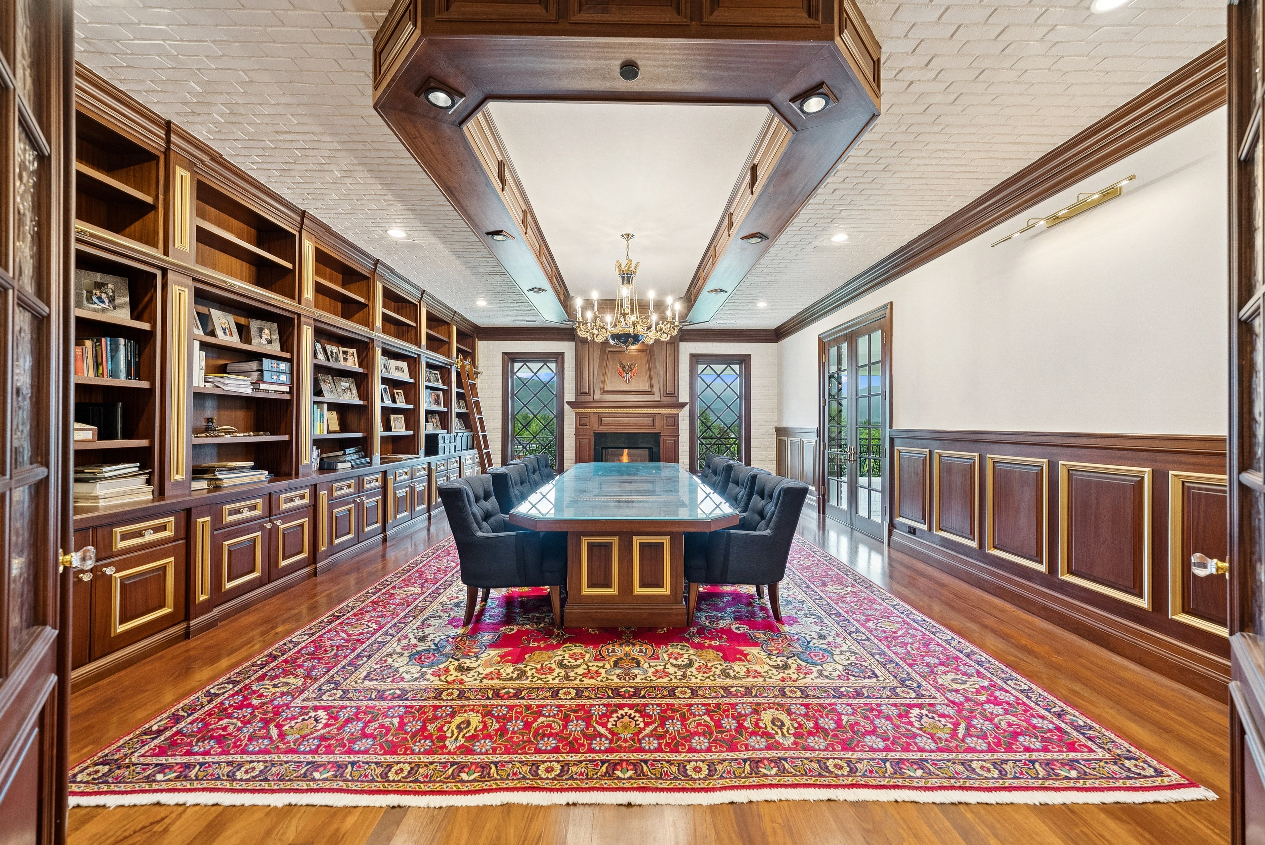 Formal room featuring extensive built-in cabinetry, polished wood-finish flooring, and a fireplace with a decorative mantel