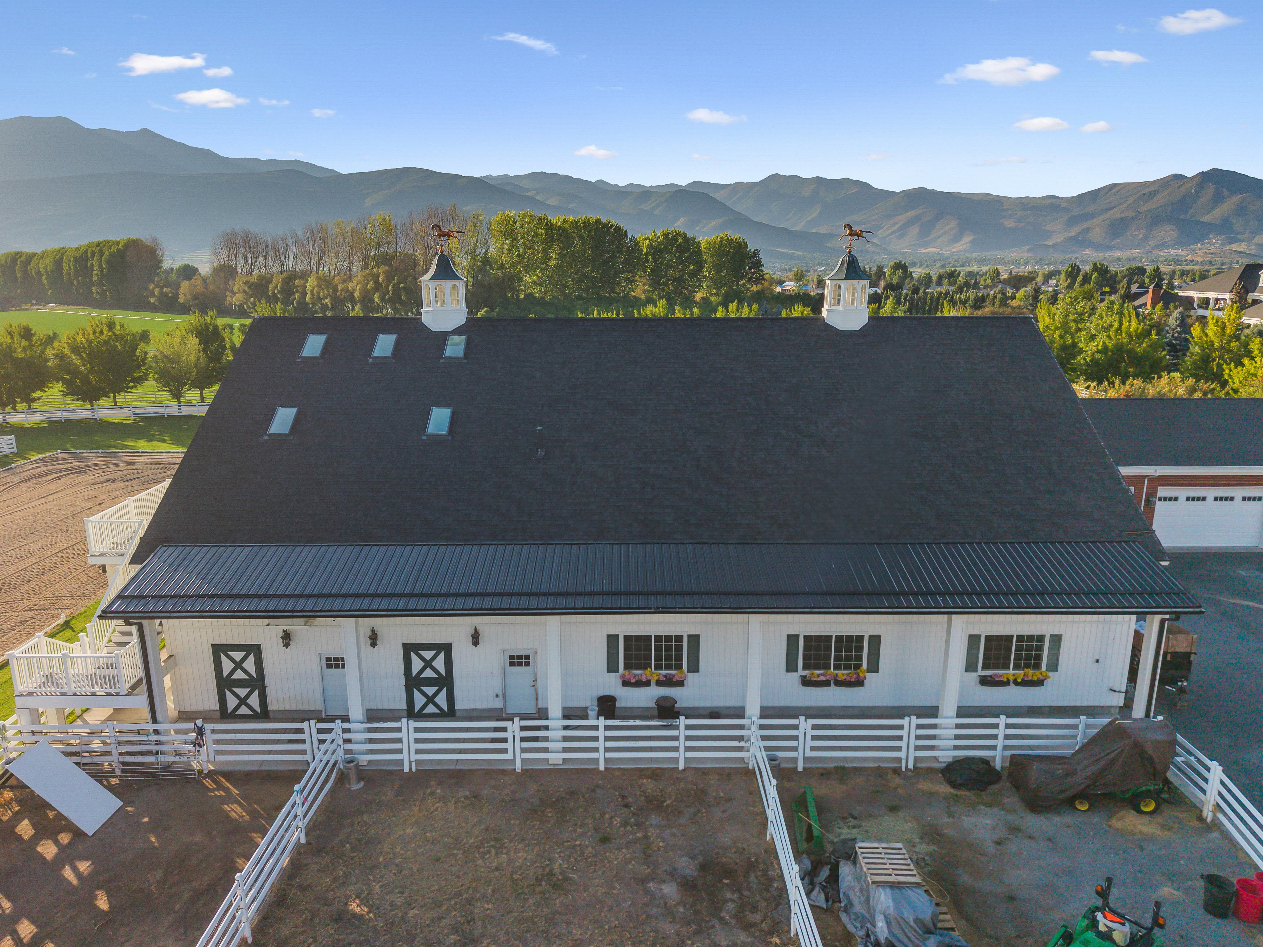 White barn structure with a dark shingle roof and metal overhang