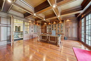 Office area with ornamental molding, french doors, wooden walls, beam ceiling, and coffered ceiling