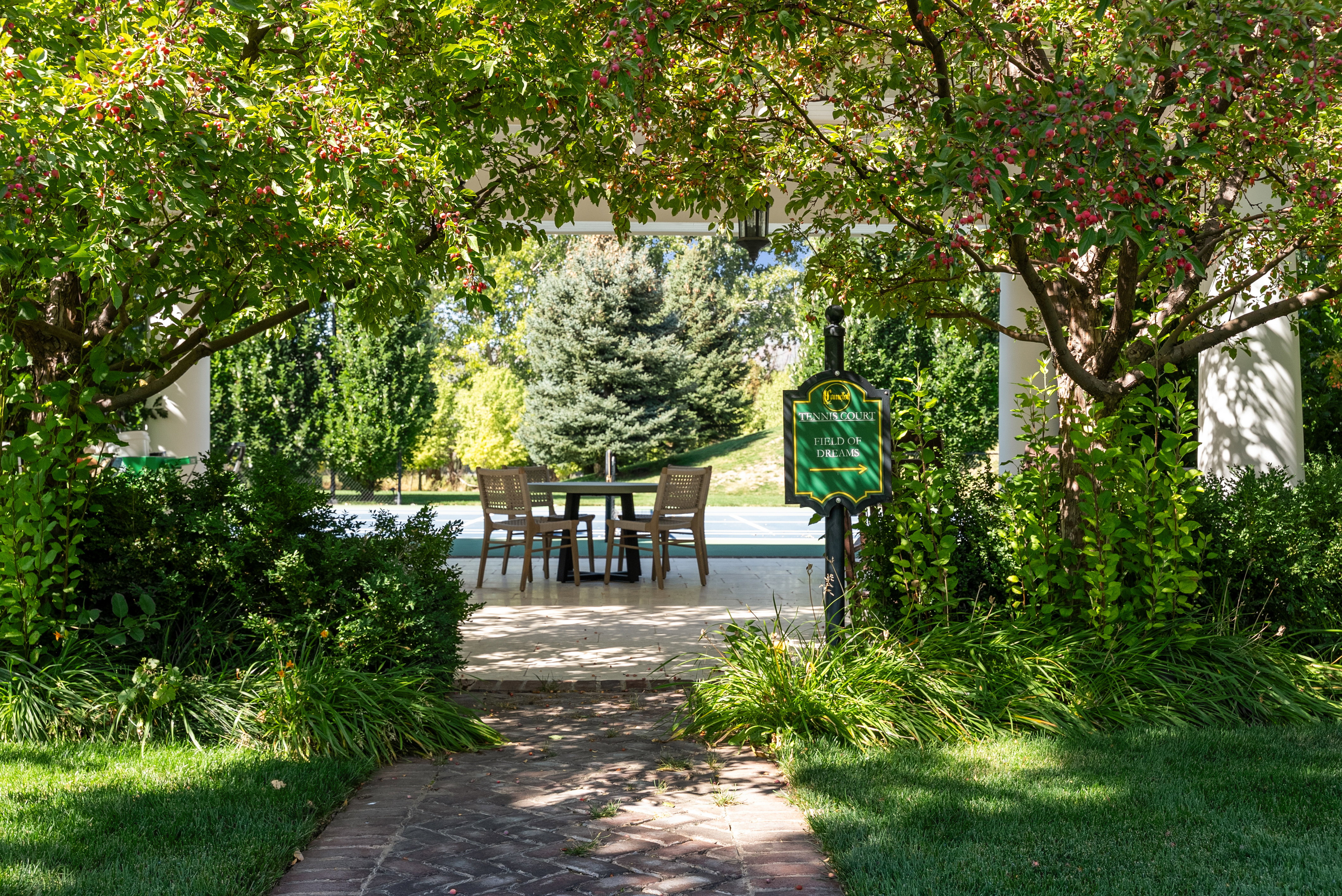 Brick pathway leading to a covered patio area with a dining table and chairs