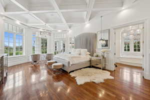 Bedroom with a decorative wall, dark wood-type flooring, a chandelier, beam ceiling, and ornamental molding