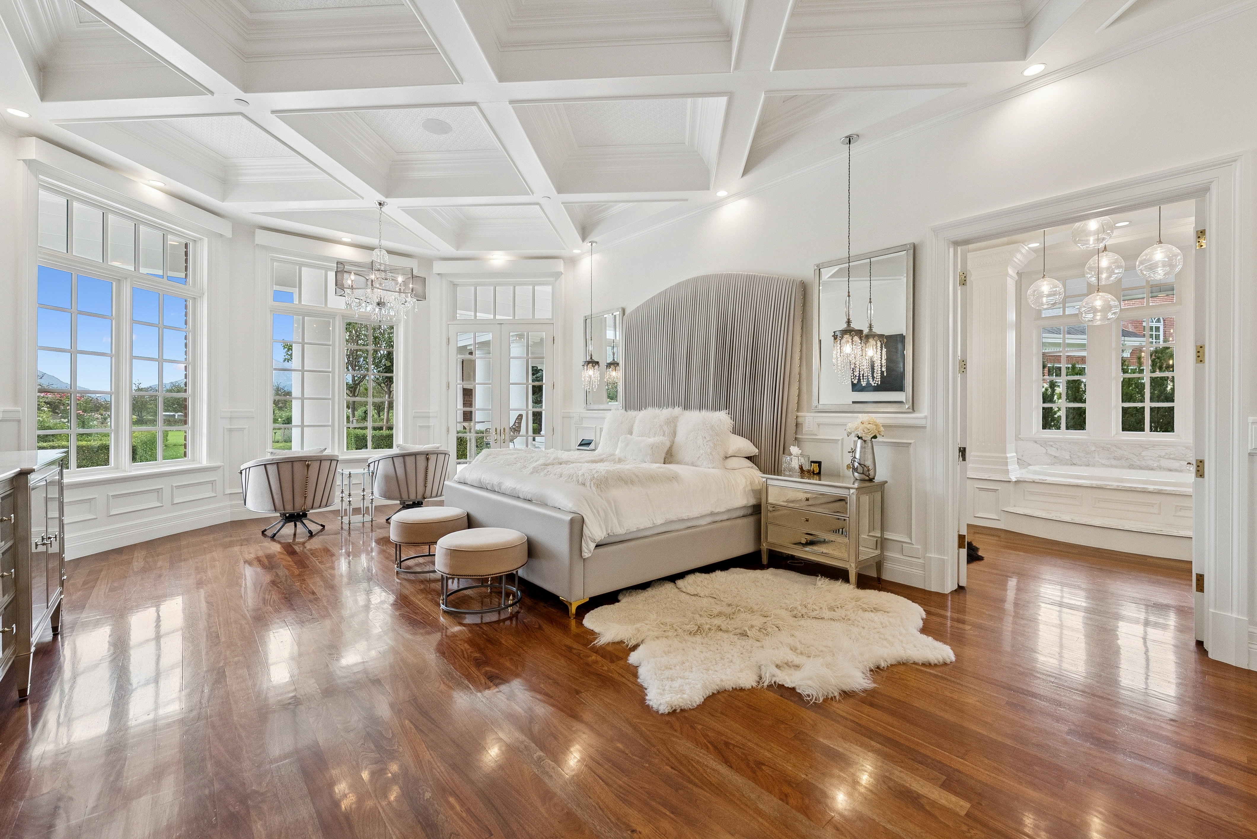 Hardwood flooring throughout a spacious room featuring a coffered ceiling and extensive wainscoting