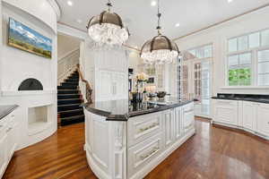 Kitchen featuring white cabinets, a kitchen island, dark wood finished floors, crown molding, and recessed lighting