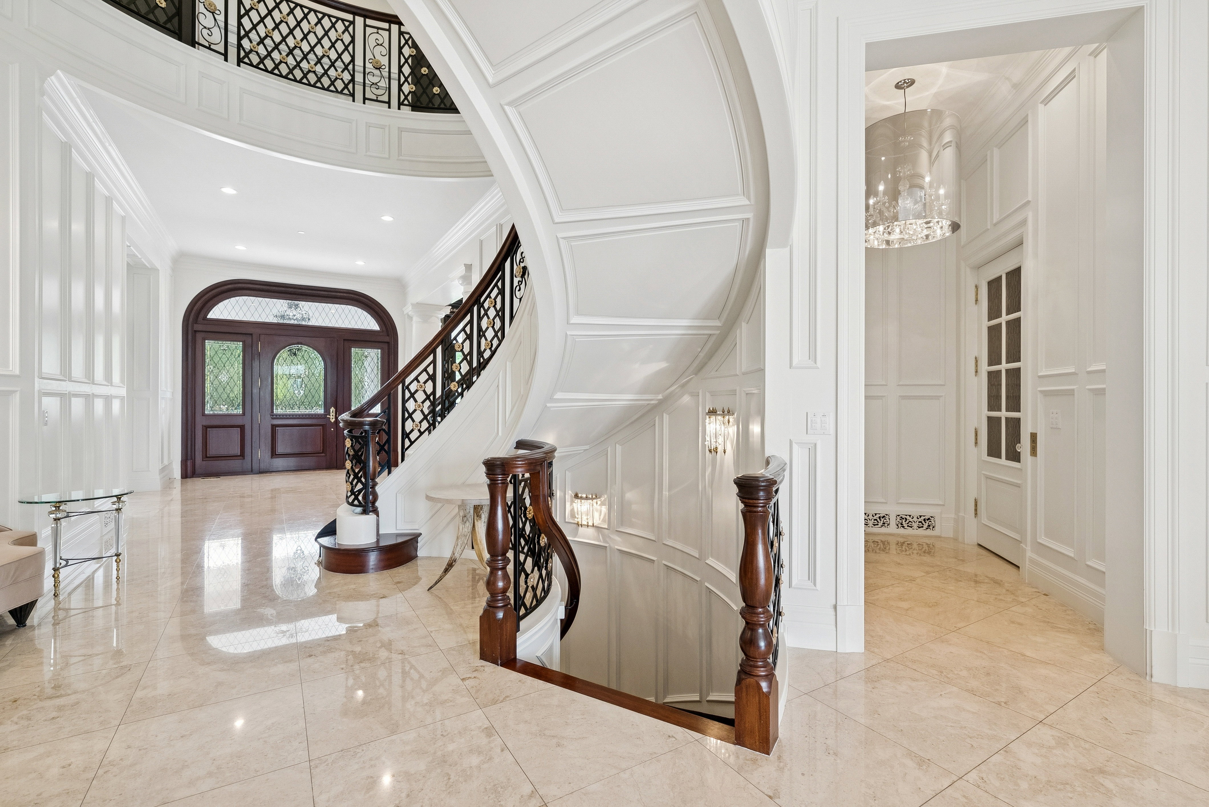 Grand foyer featuring a curved staircase with dark wood newel posts and an ornate black wrought-iron railing