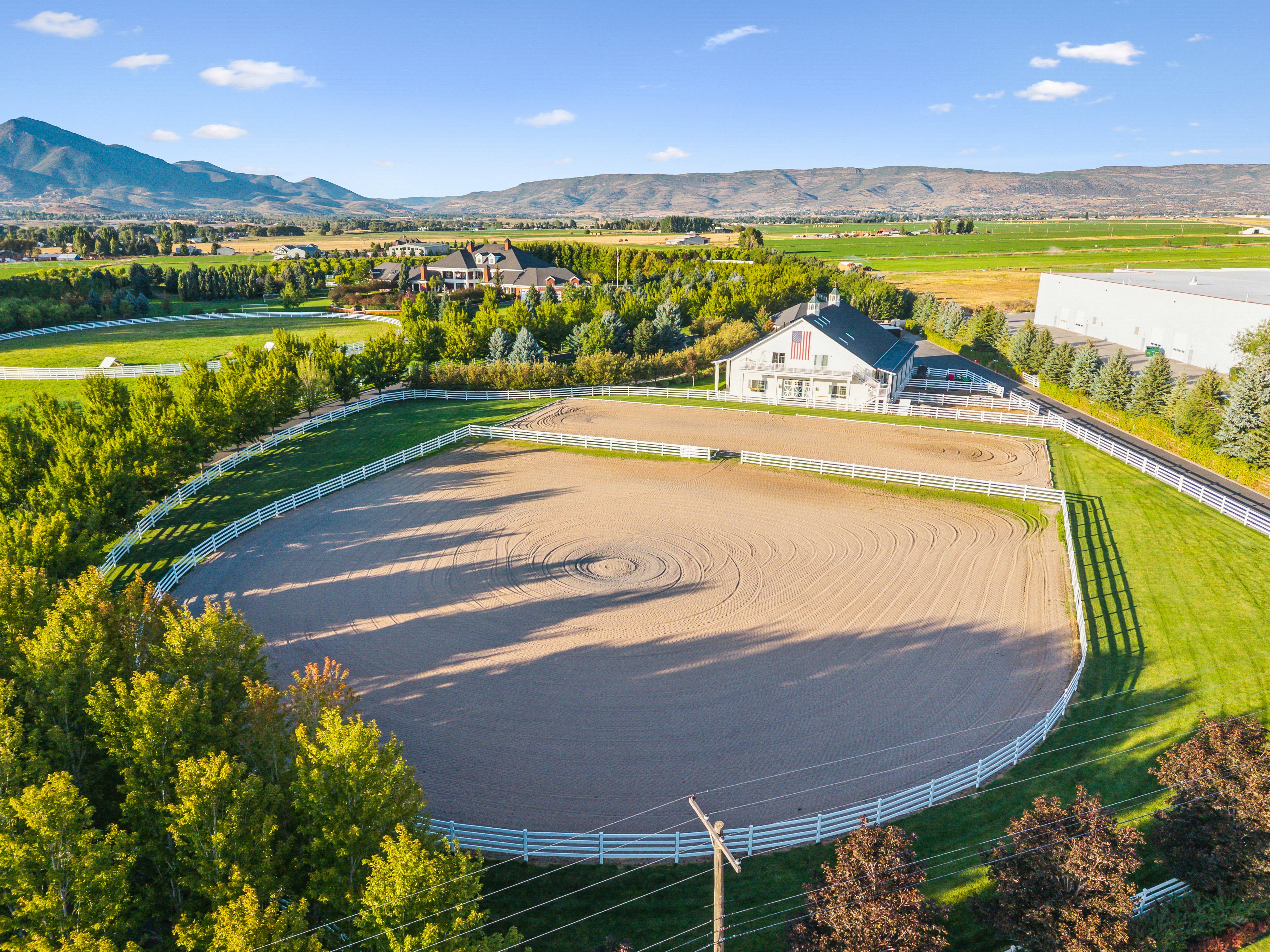 Expansive outdoor arena with white perimeter fencing