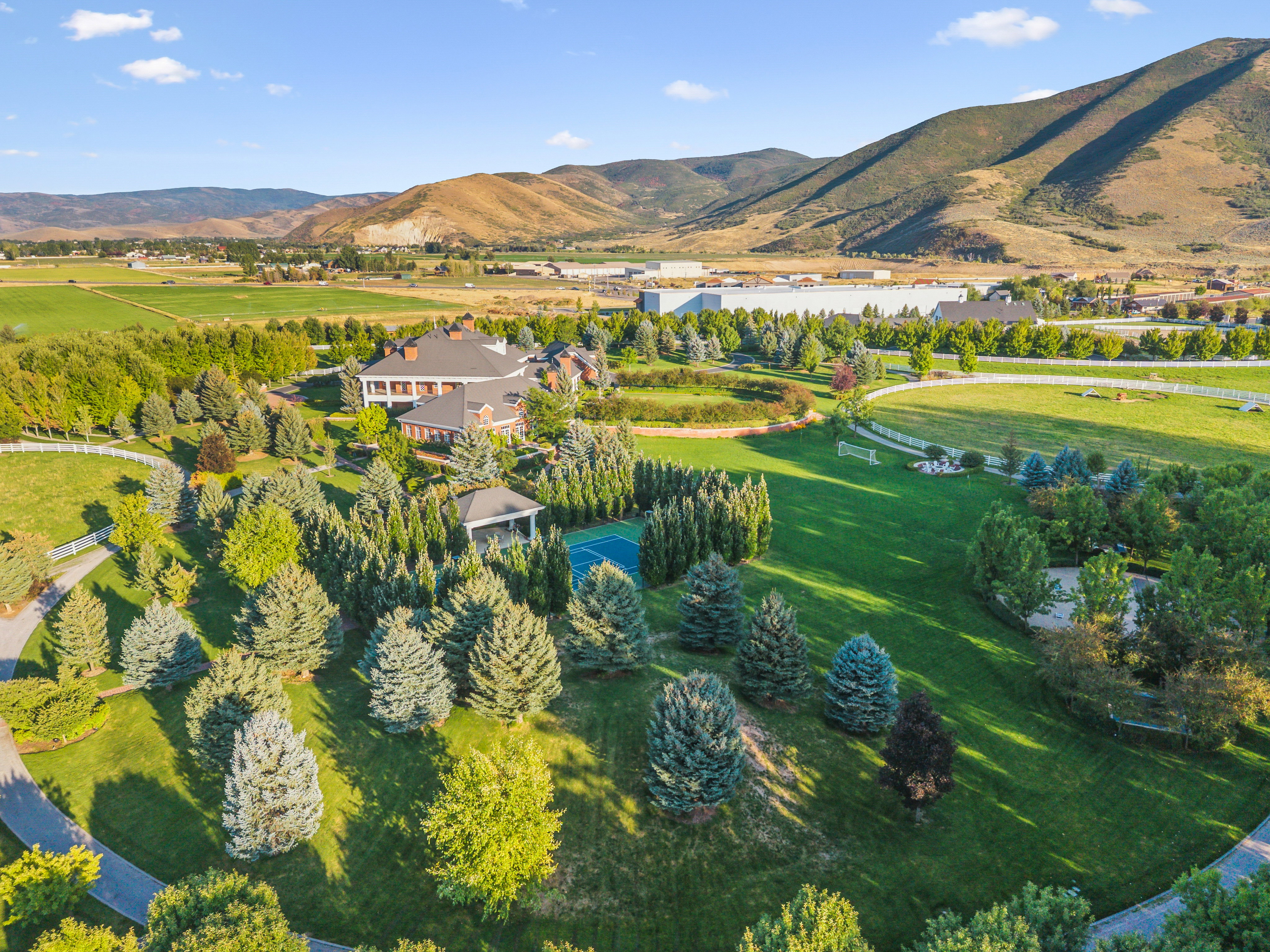 Expansive property featuring a main residence, mature landscaping, a tennis court, a gazebo, and mountainous terrain