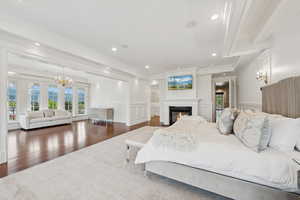 Bedroom with a glass covered fireplace, a chandelier, recessed lighting, crown molding, and wood finished floors