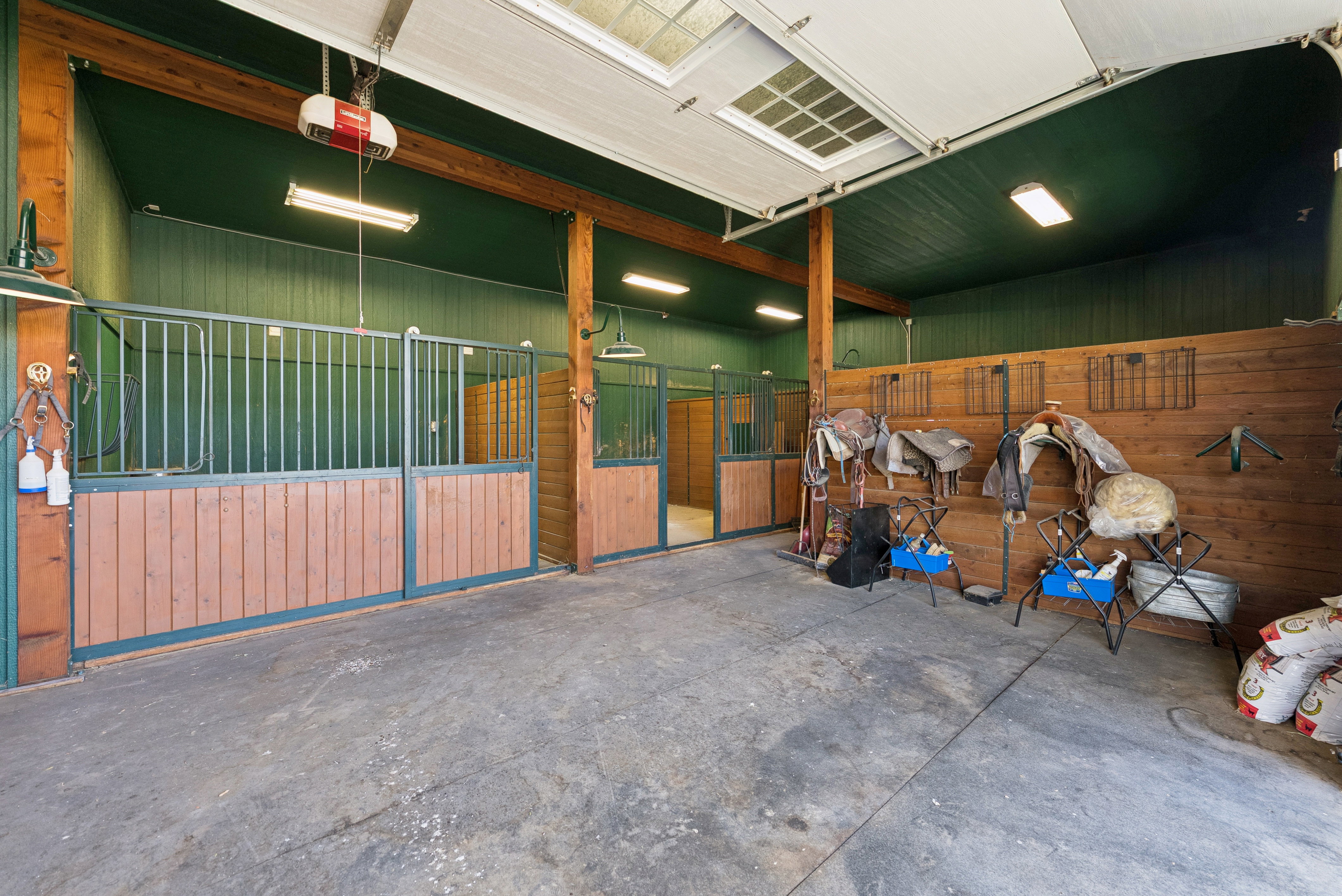 Interior stable with multiple stalls featuring wood-finish paneling and metal gating