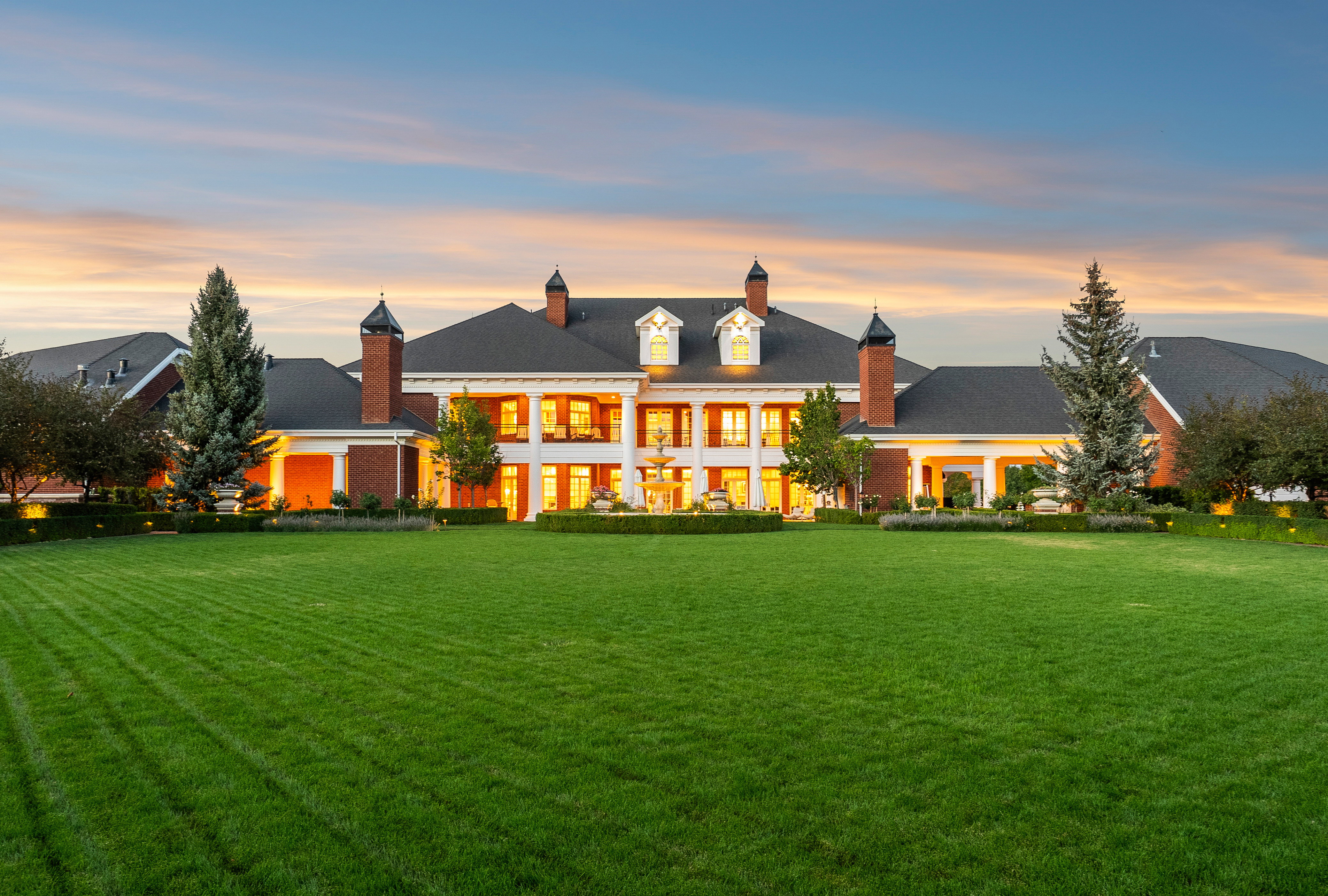 Expansive green lawn with a grand brick estate