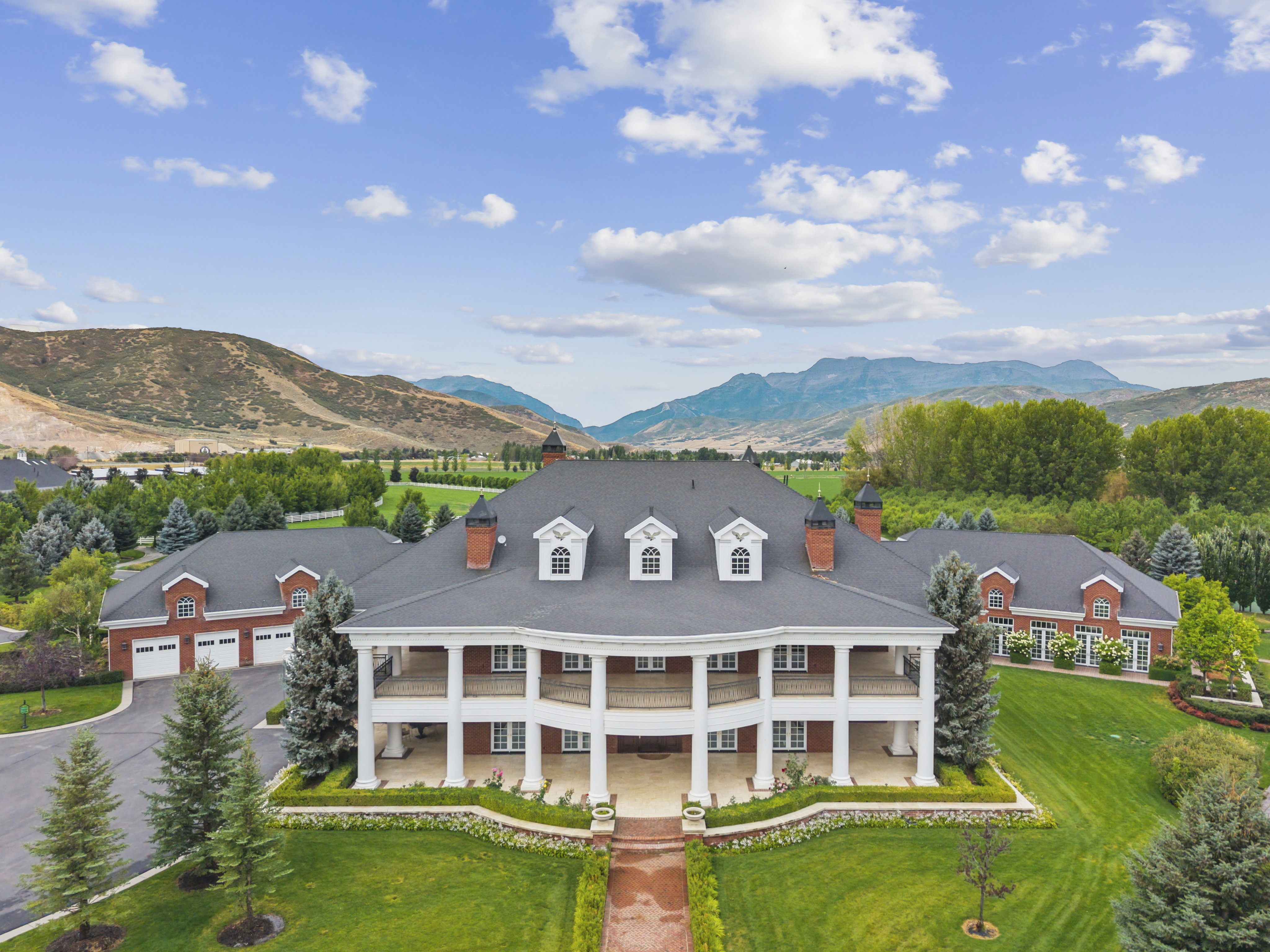Stately Colonial-style residence featuring a prominent two-story columned portico, classic brick exterior, and dark shingle roofing