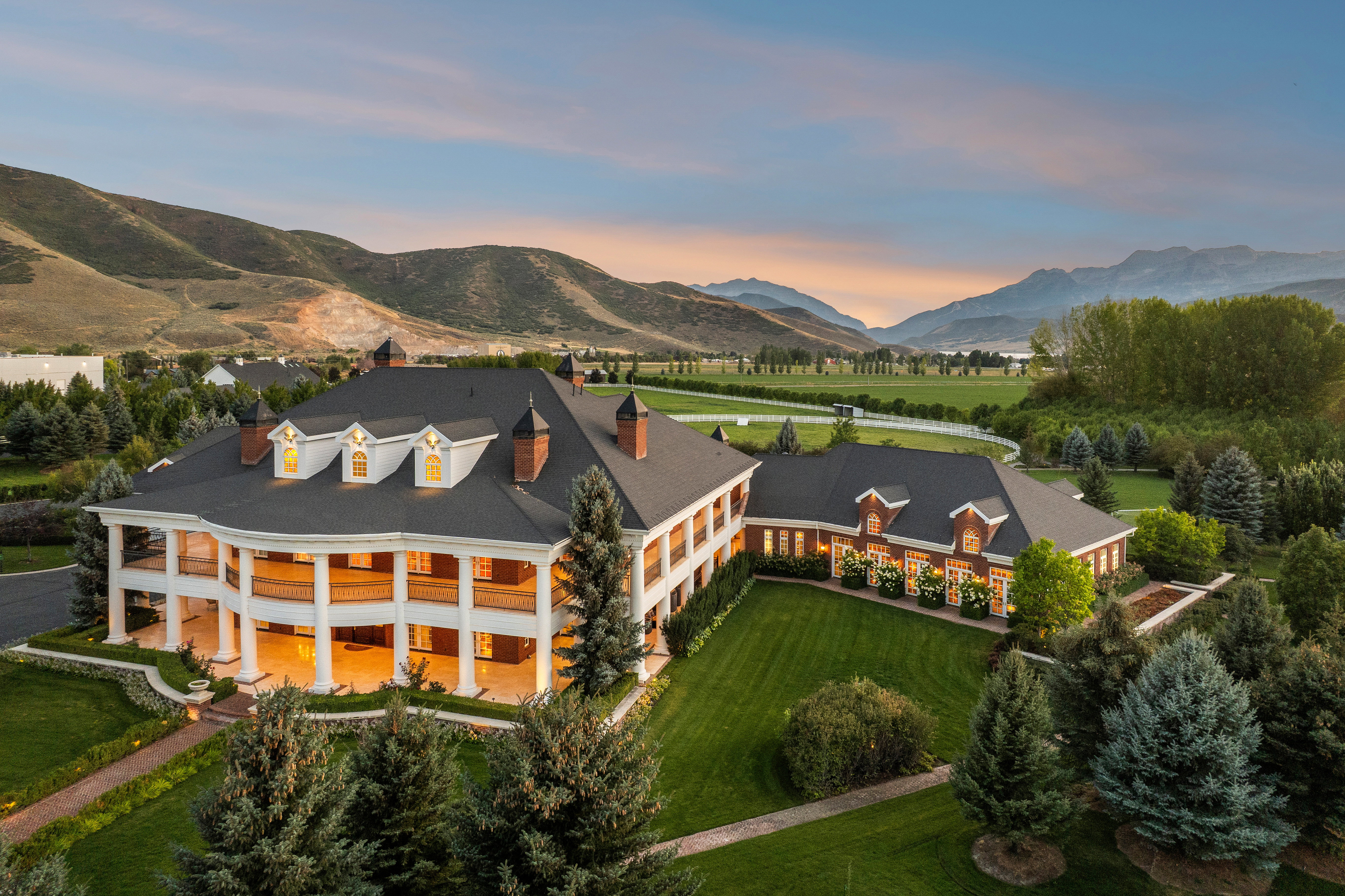 Expansive estate featuring a multi-story, white-columned facade and a distinct brick wing