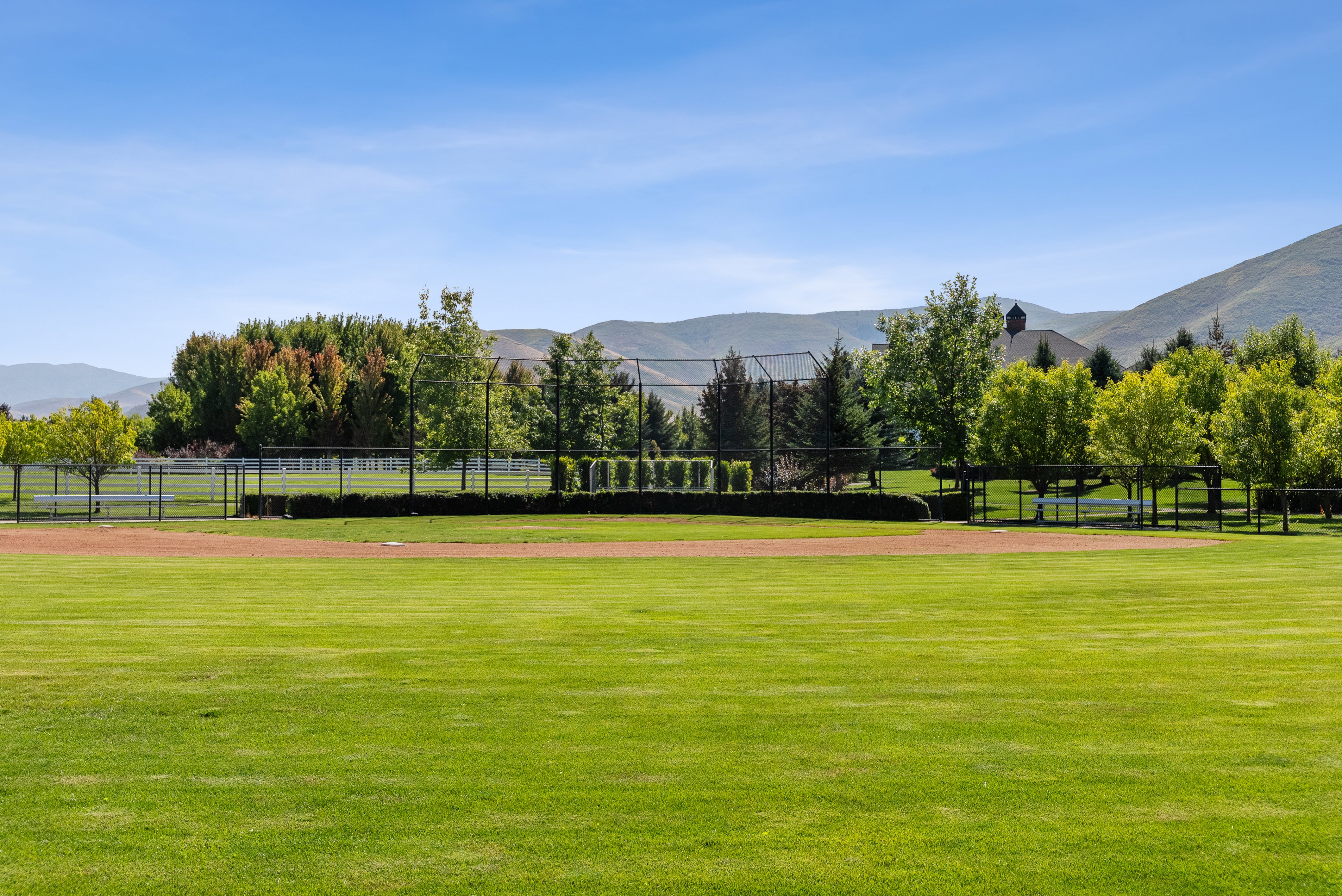Expansive green lawn with a dirt infield