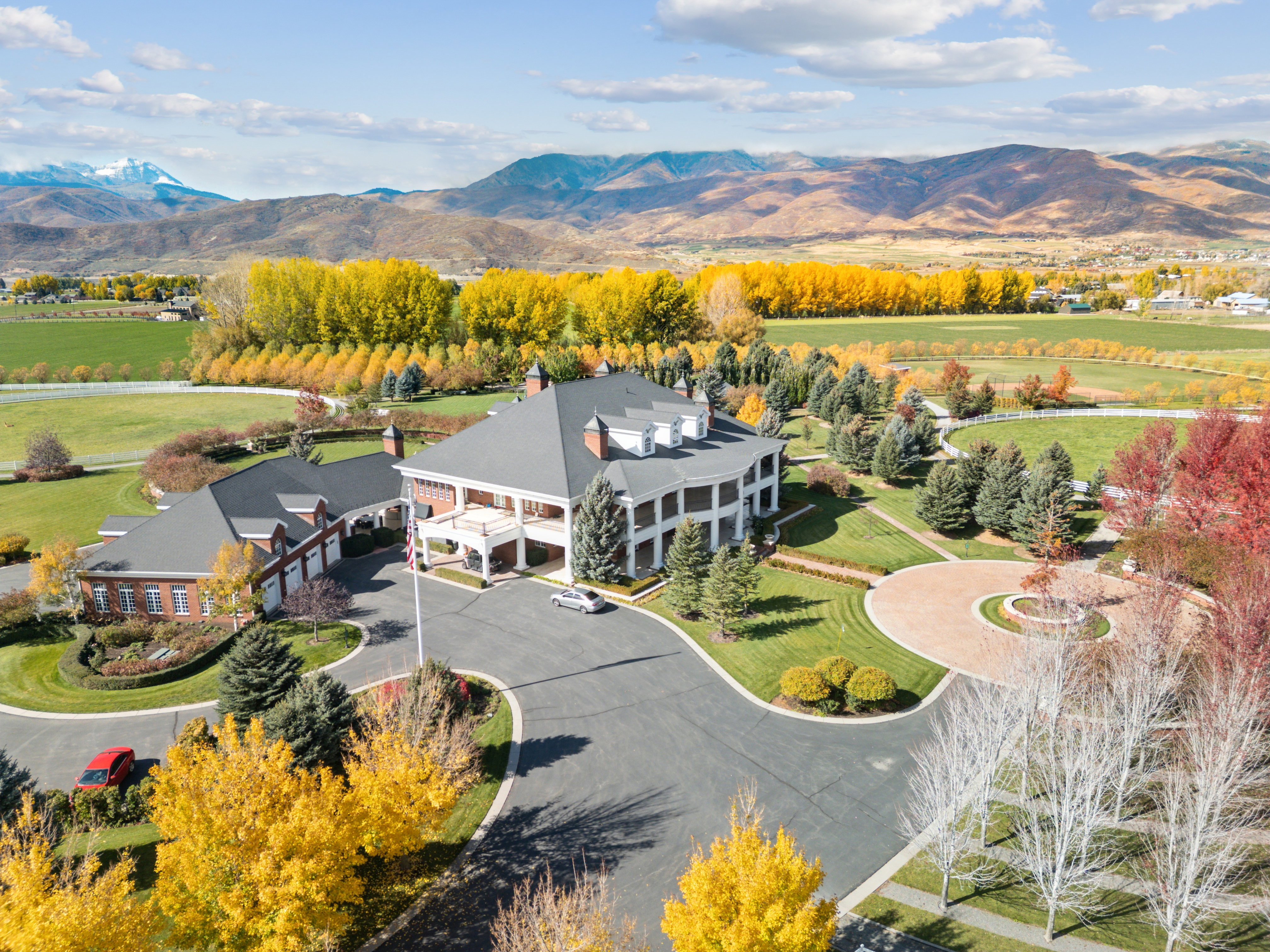 Expansive property featuring a classical white columned residence with a dark roof and a separate brick structure
