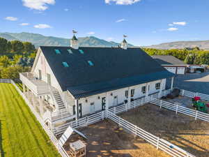 Rear view of property with roof with shingles, a mountain view, a metal roof, a fenced backyard, and stairway