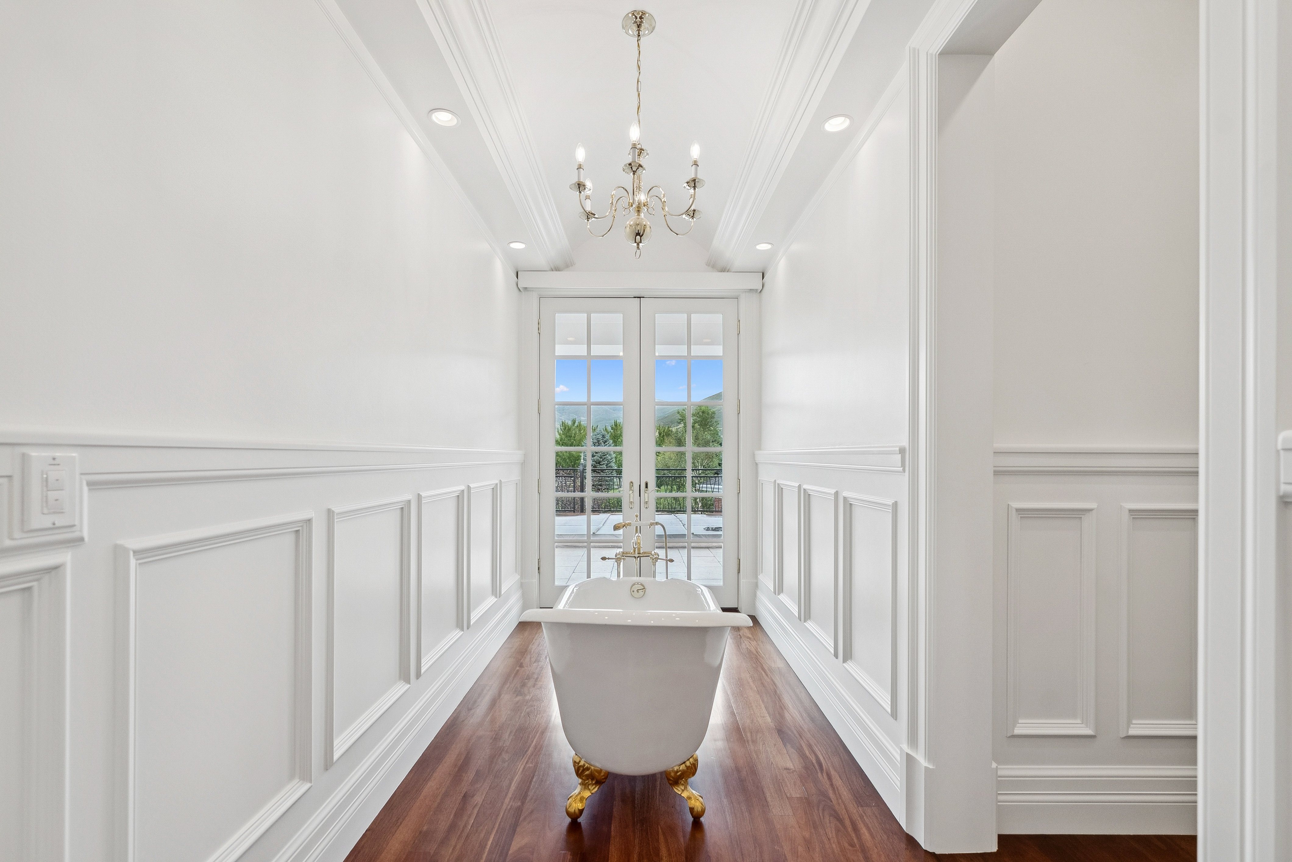 Clawfoot tub with gold-tone feet and fixtures, set on wood-finish flooring