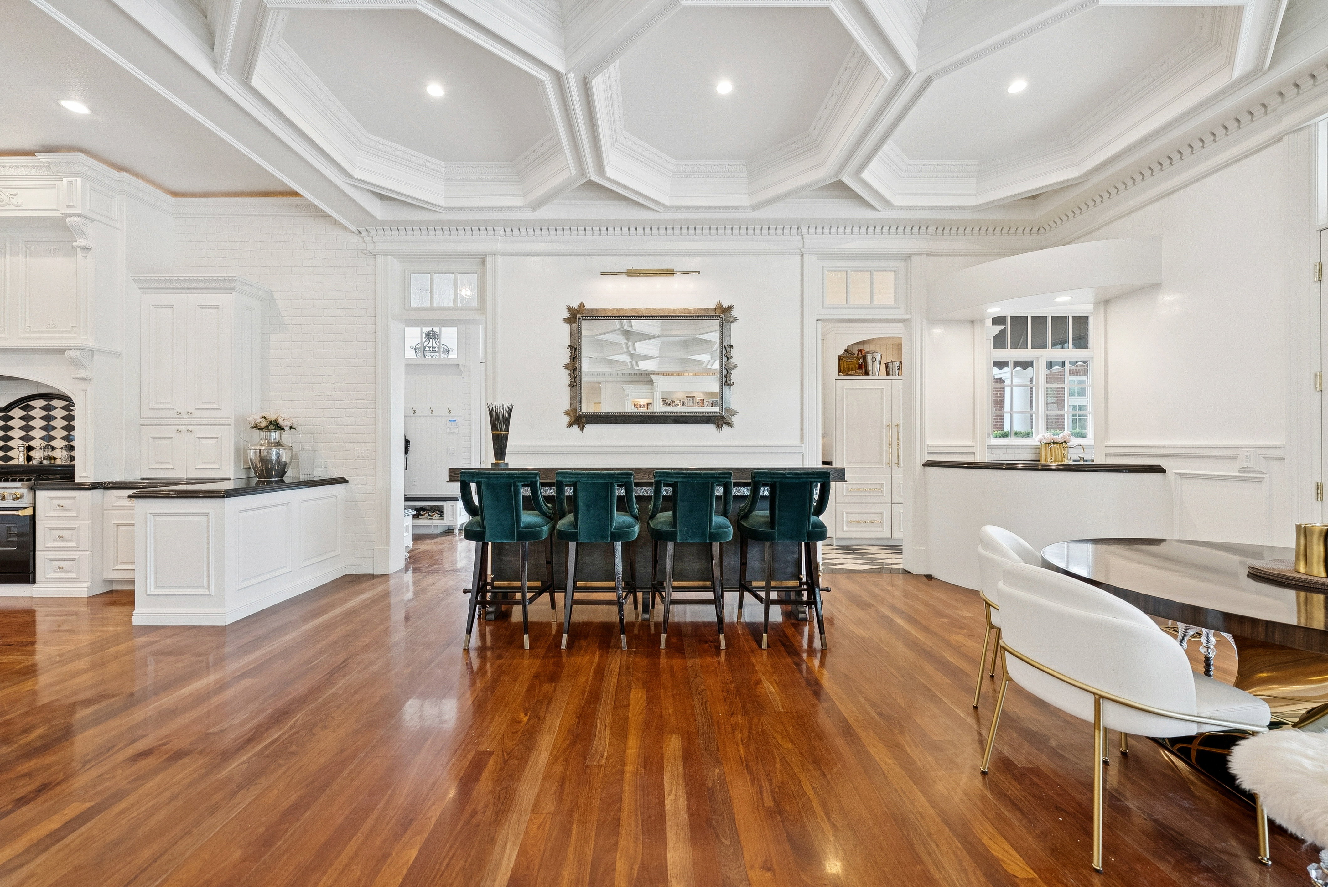 Expansive room featuring rich wood-finish flooring, intricate coffered ceilings, and detailed crown molding