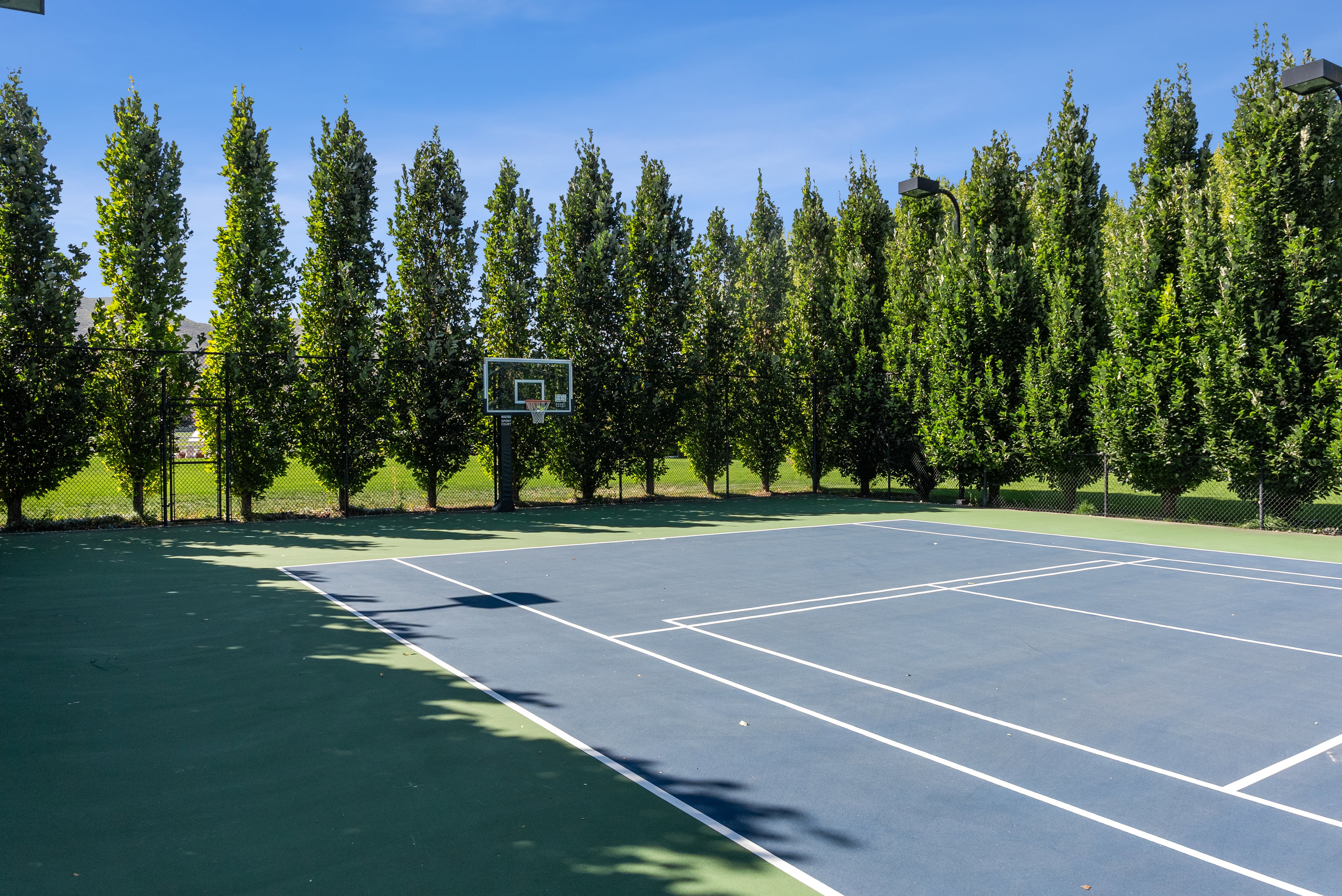 Multi-sport court featuring a basketball hoop and tennis court lines