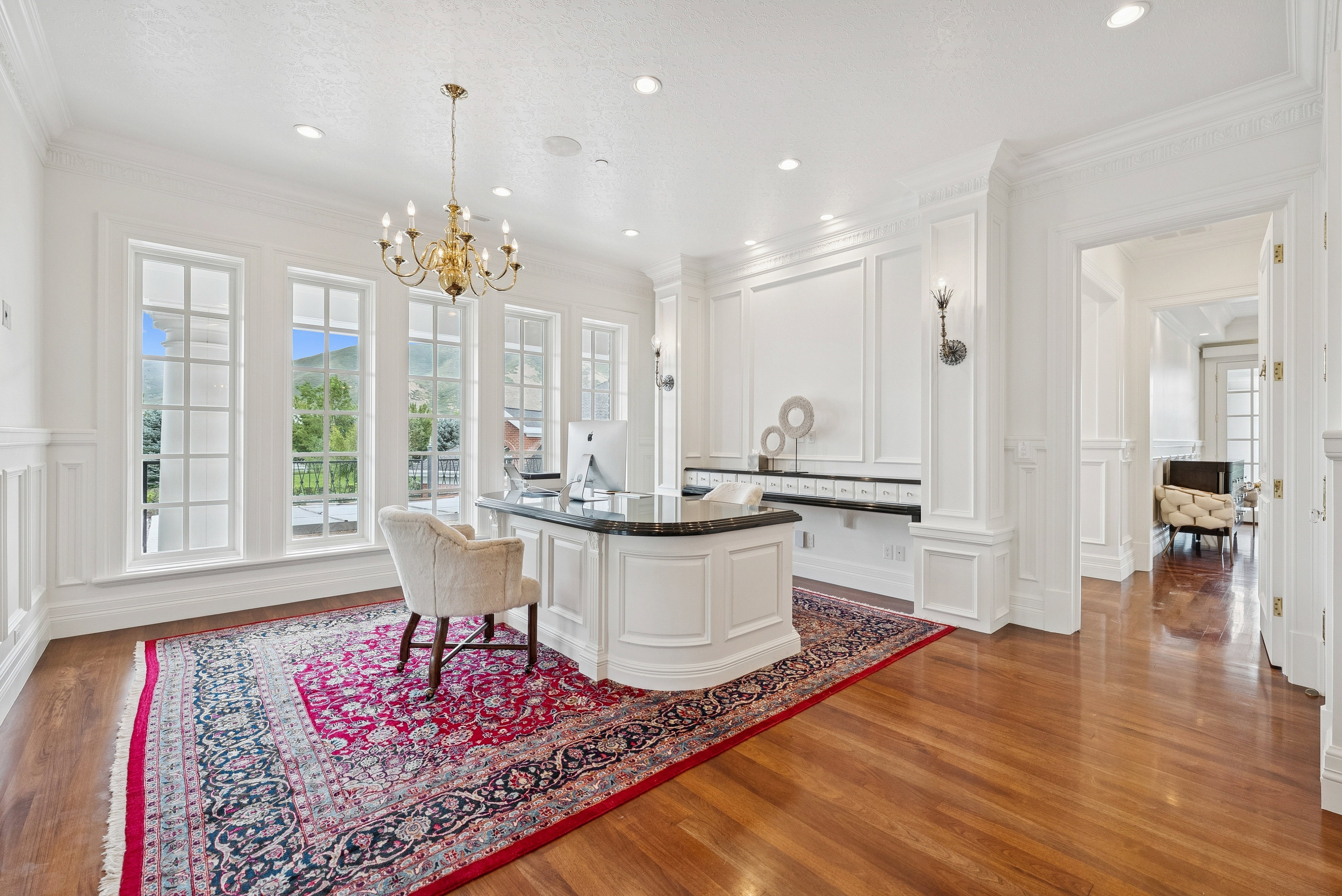 Spacious room featuring multiple large windows, rich wood-finish flooring, and intricate wall paneling