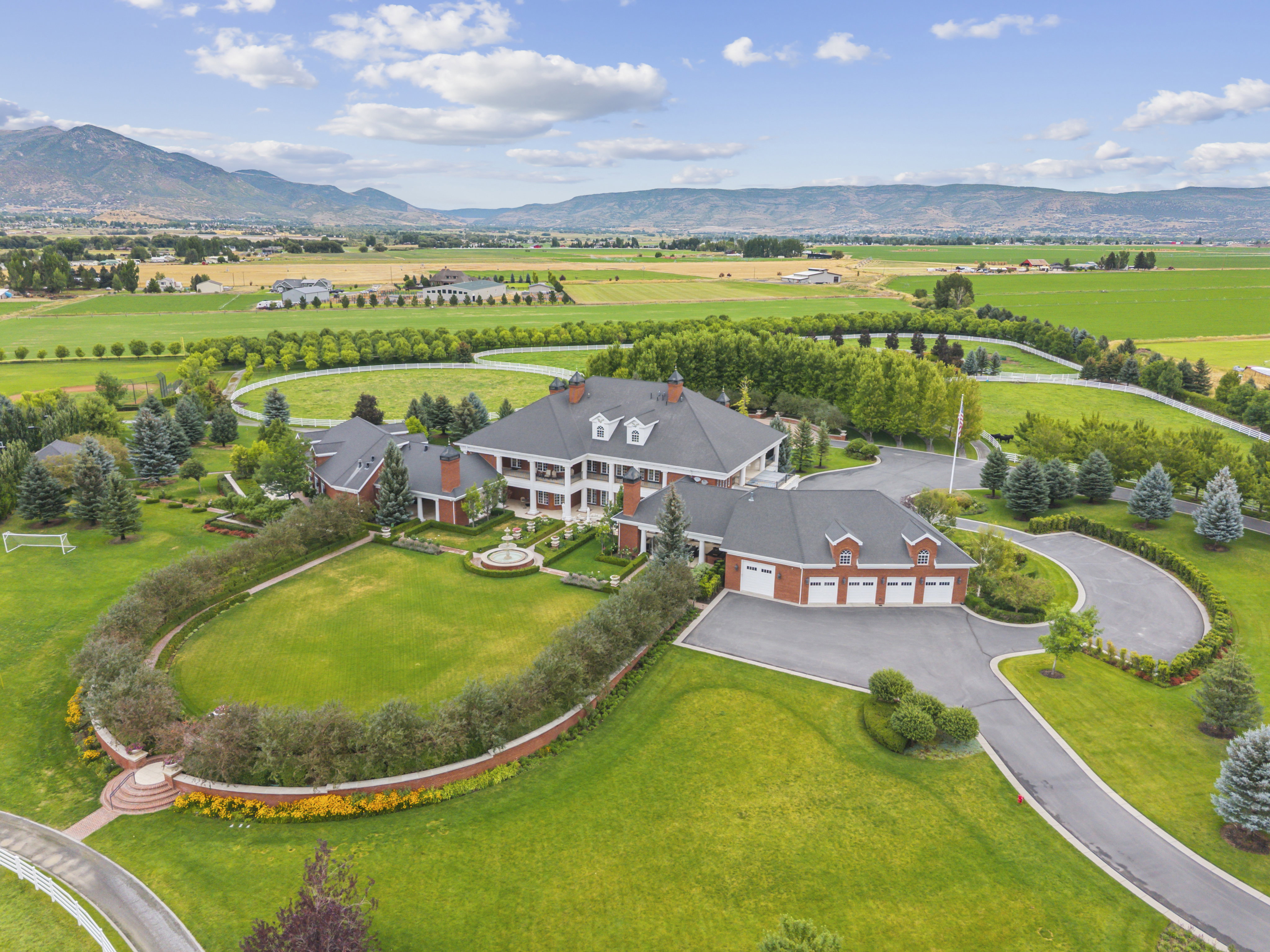 Expansive estate featuring a grand main residence with multiple dormers, a three-car garage, and extensive manicured grounds