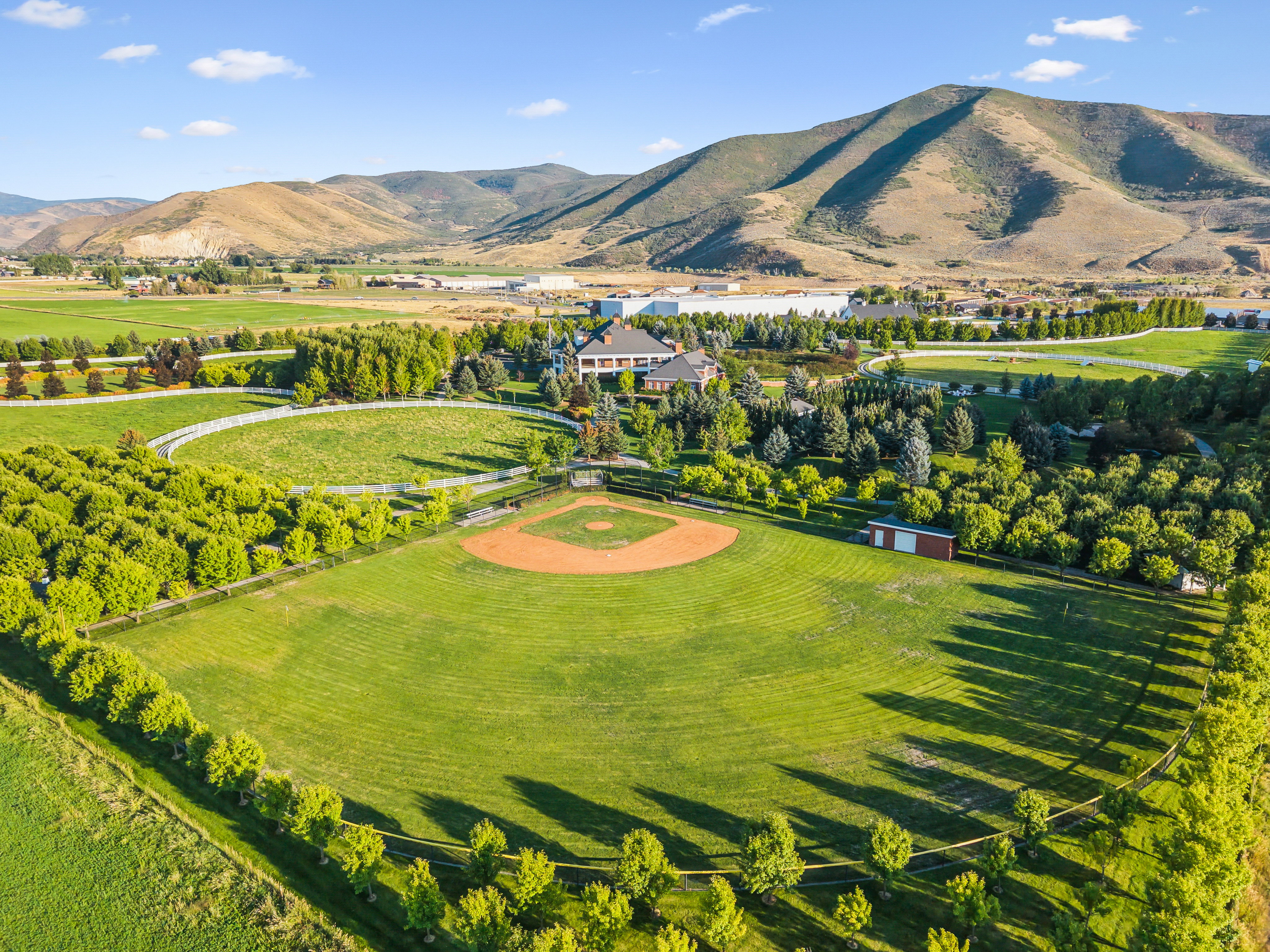 Expansive property featuring a baseball diamond with a red clay infield, surrounded by a lush green outfield