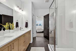 Ensuite bathroom featuring double vanity, a stall shower, and ceiling fan