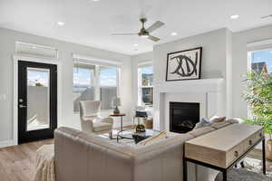 Living area featuring light wood-type flooring, a glass covered fireplace, ceiling fan, and recessed lighting