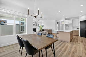 Dining space featuring a large fireplace, light wood-style floors, recessed lighting, and a chandelier